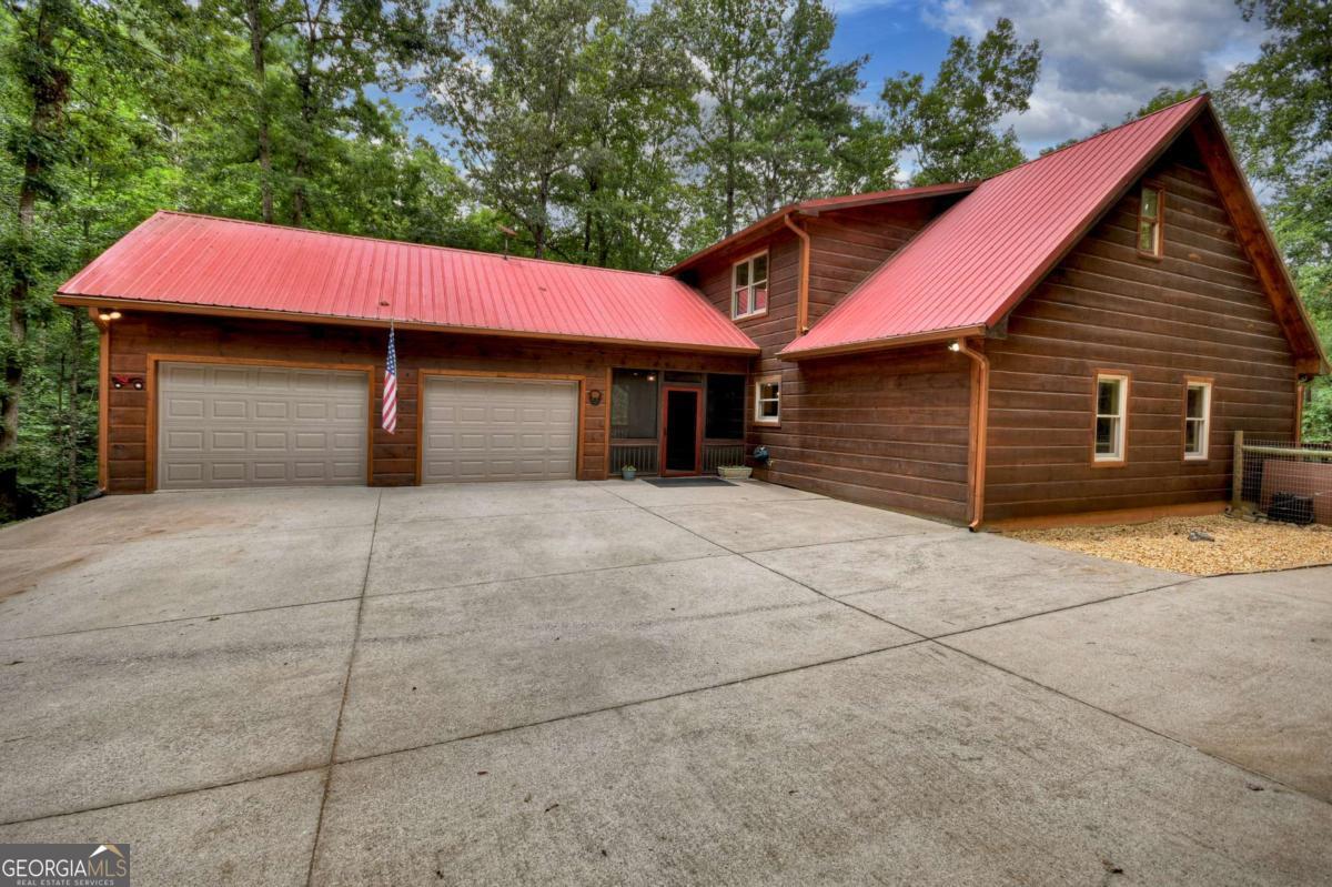 Discover rustic charm and timeless mountain living on 1.55 serene, unrestricted acres in the heart of Cherry Log. Immaculately maintained and rich in character, this spacious cabin offers over 3,800 sq ft of heated living space, with 4 bedrooms, 3.5 baths, and flexible spaces thoughtfully designed for comfort, entertaining, and everyday living. The inviting great room features soaring ceilings, a dramatic floor-to-ceiling stone fireplace, and warm wood finishes that reflect true mountain craftsmanship. The generous dining area flows into a beautifully updated kitchen with brand-new quartz countertops, custom cabinetry, and soft-close drawers-ideal for gatherings both big and small. The main level includes two spacious bedrooms and two full baths, while the upper level offers two additional bedrooms, a full bath, a large sleeping loft, and a massive attic that could easily be finished for more living space. The fully finished terrace level is a standout with its rich rustic design, offering a cozy living area, custom bar, wine cellar, and a library/game room that could serve as a 5th bedroom or private retreat, along with a half bath. This level would also make a fantastic in-law suite or private apartment, with its own spacious layout and entertaining amenities. Step outside to enjoy the screened-in breezeway, a peaceful extension of the living space, perfect for relaxing or dining al fresco. The beautifully landscaped grounds offer a tranquil backdrop, complete with a firepit area-ideal for stargazing, storytelling, and making memories. The finished 2-car garage with tongue-and-groove walls provides additional storage and charm, and a whole-house generator ensures year-round peace of mind. Lovingly cared for and move-in ready, this home is an ideal full-time residence, weekend escape, or rental investment-where nature, comfort, and mountain beauty converge.