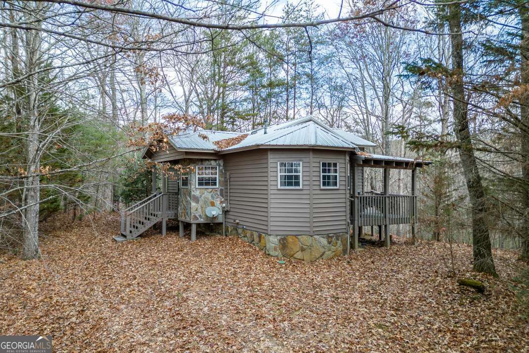 Experience the perfect blend of modern comfort and rustic charm in this fully furnished, turn-key mountain retreat-just 10 minutes southwest of downtown Blue Ridge. This inviting cabin offers a serene, wooded setting with zero lawn maintenance, enhanced by thoughtful upgrades and enduring character at every turn. Located on a winding cul-de-sac road, the exterior features classic cedar siding, a durable metal roof, and a stone skirt that blends seamlessly into the natural surroundings. Inside, the open-concept design boasts a vaulted living area with skylights, tongue-and-groove walls and ceilings, exposed beams, rich hardwood floors, and a cozy stone fireplace-ideal for cool mountain evenings. The eat-in kitchen includes a center island with a double sink and opens directly to the expansive deck through French doors, creating an effortless indoor-outdoor flow. A vaulted bedroom and a skylit, tile-finished bathroom provide bright, inviting spaces with convenient outdoor access. One of the home's standout features is the 4-season sunroom-designed for year-round enjoyment with stone flooring, walls, and steps, a vaulted ceiling, and a private hot tub to unwind in any season. Recent upgrades include a brand-new HVAC system, an advanced security system, new pipe enclosures in the crawl space, and underground cables for high-speed internet-ensuring fast, reliable connectivity while preserving the cabin's pristine natural setting. Whether you're seeking a weekend hideaway or a full-time residence, this thoughtfully updated cabin offers a rare opportunity to enjoy mountain living without compromise. Don't miss your chance to own a Blue Ridge escape that delivers both peace and performance in one unforgettable package.
