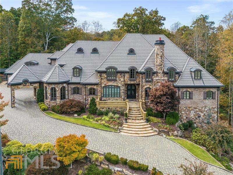 Stunning, one-of-a-kind custom built French Provincial estate on nearly an acre and adjacent to 3 unbuildable acres to the rear of the property provide a setting impossible to duplicate in East Cobb. Situated in the award-winning Walton High School District and nestled on a quiet cul de sac street just minutes to Roswell River Walk, and Downtown Roswell. The location is second to none. If craftsmanship is important, you would be hard pressed to find a better built home than Reverie Ridge. Custom built by Marshall Veal on 2x6 studs, with four sides brick and stone construction, spray foam insulation, Boral concrete roof, Kohler whole house generator, custom detail trim throughout that frames each space like a masterpiece, and 8' x 36" solid mahogany exterior doors with Ashley Norton oil rubbed bronze hardware. The Belgard paved driveway is the perfect lead into the comfortable elegance that is unmatched. From the iron double doors to the wire brushed hardwood flooring, the Jay Boston hand painted dome ceiling, the chess piece designed stair balusters, the architecture, the design, and the decor are timeless. The mic drop moment is as soon as you walk in the door with the front to back view through the all-season room to the salt water pool with hot tub and outdoor living spaces including pergola. If entertaining is a hot button prepare to be wowed by the seamless flow and thoughtful layout of this home. The fold back doors provide an expansive entry to the space that is both covered screened porch in the spring, summer and fall months and converted with glass inserts for the winter months. The hearty stone fireplace provides a space that can be peaceful or playful depending on your mood. The foyer is flanked by what is in my opinion two of the most opulent rooms in the house, the study with coffered ceiling, custom wood paneled accents and three walls of bookshelves. The formal dining room is breathtaking with its tastefully done hand painted murals on each wall. The extraordinary crystal chandelier really defines the understated opulence of this home. If you are looking for a gourmet kitchen prepare to fall in love. Custom Mouser cabinetry, leathered stone granite with contrasting polished stone counters, top of the line stainless or cabinet finished appliances including separate Subzero refrigerator and freezer, two Subzero drink drawers, two Miele dishwashers, two Wolf warming drawers, Wolf six burner cooktop and griddle top stove! Coffered ceiling family room flows seamlessly from the kitchen giving this home the unique ability to feel warm comfortable for day to day living or refined for the most elegant parties. The main level primary is tucked away from the world and is artfully designed with trey ceilings and cove lighting. The marble fireplace exemplifies the mix of old world with sleek design elements. Walking into the primary bath with its heated floors, custom cabinetry with built in and hidden electrical drawers, double vanities, granite counters, separate whirlpool tub and open shower also with heated floors with so many sprayer options you may not want to leave. The primary closet offers an abundance of hanging, display and storage options with easy access to one of the three laundry rooms in the house. Upstairs you will find a second primary suite option, two additional guest suites and a fully outfitted gym and kitchenette. The terrace level includes a second kitchen, rec room, bedroom suite and art studio. Obviously... I could go on and on about this spectacular home, but it needs to be seen in person to be appreciated.
