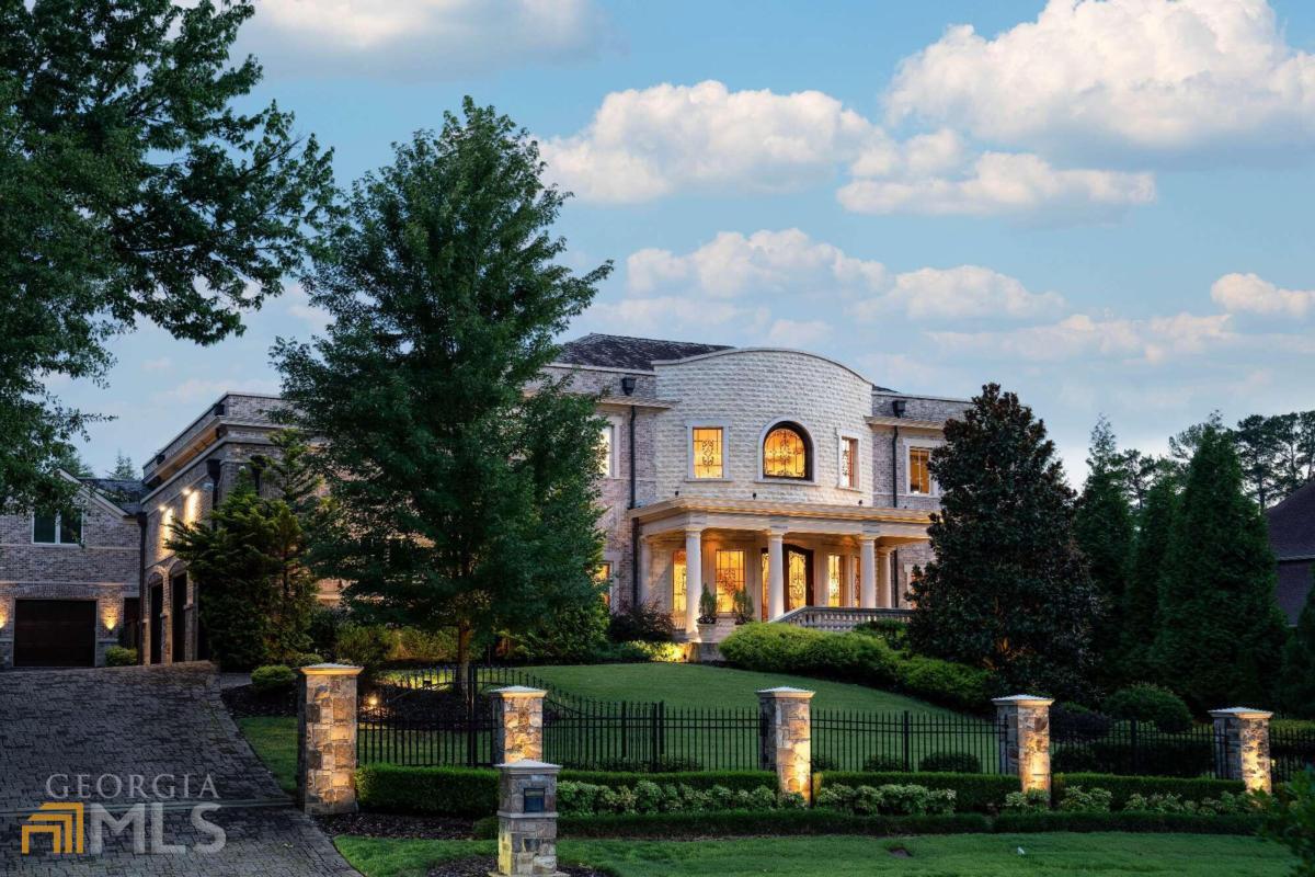 Nestled in a quiet cul-de-sac in Atlanta Country Club and adjacent to a 20-acre McFarlane nature park, this custom estate home was designed for top-of-the-line living. Built in 2009 and designed by Harrison Design, this construction was a 3-year labor of love that spared no expense. With materials sourced and imported from all over the world, this home offers a masterfully curated space that can be appreciated on every level, and down to every last detail. At over 14,000 square feet, this property features 7 bedrooms, 9 full bathrooms and 5 half bathrooms, as well as a 4-car garage and elevator access to all three levels of the home. The inviting foyer and expansive formal rooms feature 24-foot ceilings that provide a spacious layout perfect for entertaining, while still maintaining a cozy atmosphere. The main level owner's suite boasts a barrel vault ceiling, enormous walk-in closet, and a built-in spa complete with a hot tub, steam room and sauna leading to the pool area. The three upper bedrooms each feature ensuite baths, and also include a private living quarters with a full kitchen, laundry room, and bedroom suite. The upper level has an In-Law/Au-Pair suite, with a private bathroom, separate entrance, and direct single car garage access. The kitchen combines gorgeous, modern design with state-of-the-art appliances to create a space that is equally inviting and practical. With a fully equipped gym, cozy home theater, and secondary family rec room with a projector and pool table, amenities abound for families of all sizes. At just under an acre, the property's meticulously manicured grounds display a gorgeous street presence while also providing privacy for residents. The stunning, walk-out backyard is perfectly suited if you're looking to relax and unwind, as well as entertain. The saltwater pool with a Pebble Tec finish, LED lighting, and remote-controlled waterfall features creates a gorgeous atmosphere, and the perfect complement to the outdoor dining area and Pool House. Once you see it for yourself, it's no surprise this house's construction was a 3-year undertaking. With unwavering attention to detail, this home ensures luxurious comfort and unparalleled quality that every member of the family will appreciate.