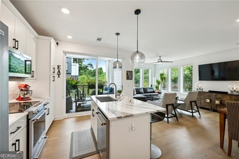Pratt Stacks - Amazing opportunity to live in historic Grant Park next to the popular Beacon for shopping, dining and entertainment. Better yet, you'll be located in the back of the community directly on the Beltline you can see from your living area. This corner unit is full of natural light and windows galore! Light natural 7" plank hardwoods throughout, open concept floor plan with crisp, white kitchen with quartz counters, subway backsplash, high-end KitchenAid appliances, pantry, center island, sliding doors to charming covered porch, laundry closet fits side by side W/D with cabinetry storage, coat closet, two walls of windows in the living room, over-sized primary suite with large custom designed closet with hamper and shoe shelves, primary bath w/ huge walk-in shower, water closet, linen niche and double vanities with quartz and custom mirrors. Spacious guest bedroom with walk-in closet and triple windows. White guest bath with shower and penny tile. Extra storage closet under the stairs. Single car garage w/ large storage room, remote controlled rolling shades throughout, WIFI dimmers, NEST thermostat, one of the few units with a FULL DRIVEWAY that will fit another car. Impeccably taken care of and improved - shows like a model home!