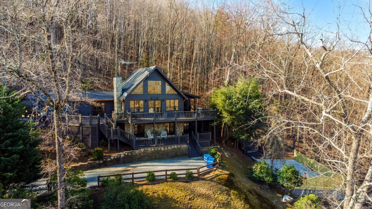 YOUR DREAM MOUNTAIN LAKE RETREAT AWAITS! Just added a new PICKLE BALL COURT on property! Breathtaking lake and mountain views surround this stunning rustic cabin, inspired by traditional Italian architecture and designed for year-round beauty and relaxation. Whether you're sipping coffee on the expansive upper deck or unwinding on the cozy lower deck, every angle offers a spectacular backdrop of nature's finest. Step inside to a grand open living space, where a charming wood-burning fireplace sets the perfect ambiance. The chef's kitchen is fully updated with stainless steel appliances, sleek granite countertops, a wine fridge, and a spacious walk-in pantry-ideal for entertaining. The main-level master suite is a private oasis, offering direct access to the deck with breathtaking lake and mountain views. Indulge in the spa-like master bath featuring a soaking tub, beautifully tiled shower, double vanities, and luxurious HEATED FLOORS. Upstairs, a private loft bedroom and en-suite bath create a serene escape, while the finished basement boasts two additional bedrooms, a full bath, and plenty of storage. Every detail has been thoughtfully upgraded, including a brand-new hot tub, new HVAC system, upgraded well equipment and plumbing, plus a freshly painted home and deck. Located just 10 minutes from downtown Blue Ridge, this cabin is SOLD FULLY FURNISHED AND TURNKEY, making it perfect as a luxury getaway or an income-producing rental with a strong rental history. This is more than a cabin-it's an experience. Don't miss your chance to own this mountain-lake paradise!