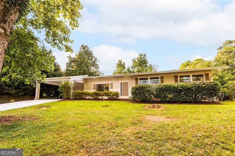 Nestled in the highly sought-after Lavista Woods neighborhood of Tucker, GA, this charming mid-century modern home offers the perfect blend of serene living and urban convenience. Surrounded by beautifully updated homes, manicured lawns, and tree-lined streets, Lavista Woods exudes a strong sense of community and tranquility, yet it's just minutes from Northlake Mall, diverse dining along Lavista Road, and the recreational haven of Henderson Park with its trails and sports fields. With easy access to I-285, Atlanta's vibrant downtown is within reach, making this location ideal for families and professionals alike. The home itself boasts new insulated windows and stunning white oak hardwood floors that flow throughout its thoughtfully designed 3-bedroom, 2-bathroom layout. Additional space includes a full dining room, separate living area, mud room and breakfast area. A private level backyard provides a serene space for outdoor relaxation or entertaining, while a covered carport offers convenient and protected parking. The unfinished basement adds versatile space, perfect for storage, a workshop, or a creative retreat, allowing you to customize it to your needs. This well maintained residence is a canvas awaiting its new owner's personal touches to transform it into a true haven. Don't miss the opportunity to own a piece of Lavista Woods' charm, where community, modern comfort, and natural beauty converge. Come see this beautiful home in a neighborhood where properties rarely come available on market today!
