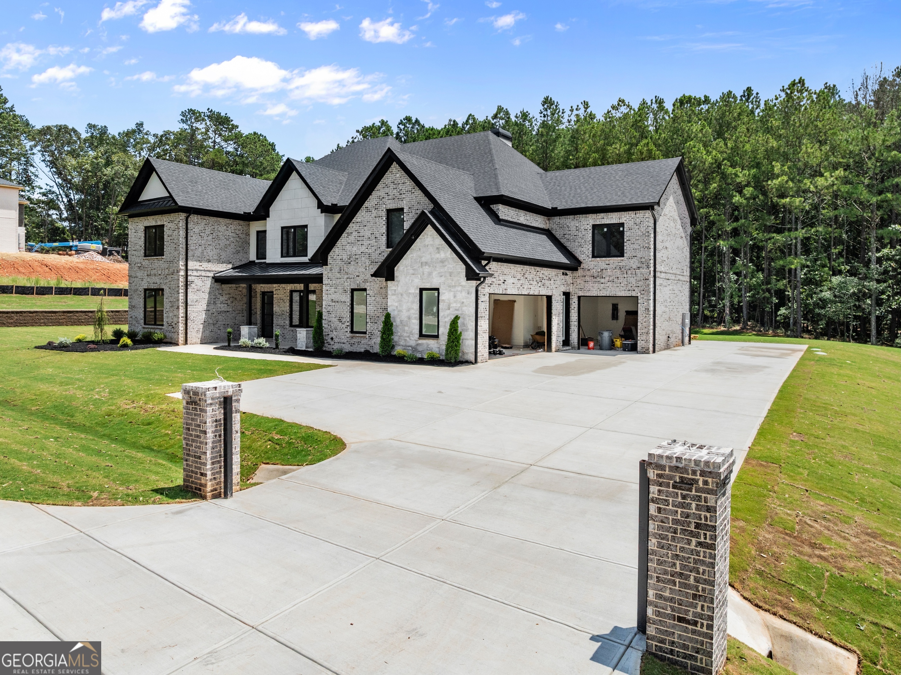 A Masterpiece of Timeless Design & Modern Performance! Welcome to a distinguished estate where exceptional craftsmanship meets high-performance living in one of North Georgia's most desirable communities. Located in the award-winning Mill Creek School District, this custom luxury residence offers a rare blend of architectural elegance, advanced energy efficiency, and private gated serenity. Clad in classic brick and sealed with spray foam insulation, this meticulously designed home boasts European-inspired tilt-and-turn double-pane windows and premium doors that block UV rays and reduce exterior noise-ensuring year-round comfort and quiet sophistication. Step inside to a grand interior that radiates luxury and thoughtful design at every turn. The main living area, anchored by a large hand-laid stone, wood-burning fireplace, is ideal for both intimate family moments and grand-scale entertaining. The gourmet kitchen is a culinary dream-featuring custom cabinetry, designer finishes, and professional-grade appliances. A hidden scullery just behind the kitchen provides discreet space for prep and cleanup, allowing your entertaining space to remain flawless. Retreat to the luxurious owner's suite-a private sanctuary with a soothing color palette, custom finishes, and a separate sitting room with its own fireplace and fully equipped morning bar. Every detail is designed for relaxation, style, and elevated comfort. Enjoy movie nights in the dedicated theater room or host unforgettable gatherings on the covered outdoor patio, complete with an outdoor kitchen, prep station, and built-in refrigerator-perfect for alfresco dining under the stars. Solid core doors throughout add another level of sophistication and privacy, reinforcing the home's emphasis on quality and soundproofing. Secluded yet connected, this estate offers the best of both worlds-tranquil living within minutes of premier schools, shopping, and dining. Whether you're looking for a forever home or a sound investment in one of Georgia's most sought-after areas, this estate is a rare opportunity to own something truly exceptional. A refined, enduring estate where timeless luxury meets modern ease. Schedule your private tour today and experience it firsthand.
