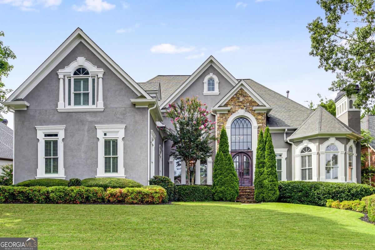 Class, comfort and convenience; this home exudes all three. Situated among the tree-lined streets of the private, guard-gated St Ives Country Club community sits this stately, European-style home. The mature landscaping and stunning curb appeal of the hardcoat stucco and stone exterior greet you upon arrival. Enter through the custom arched iron front doors and into soaring ceilings, abundant natural light, gleaming hardwood floors, extensive custom millwork and designer touches throughout. The thoughtful floorplan seamlessly blends formal and casual spaces. Pass by the vaulted fireside room in the front of the home that's ideal for a large home office, formal living room, music room or library. The two-story great room features a second fireplace, custom built-ins and a wall of windows that overlooks your private backyard oasis with a huge open-air deck, flat backyard, heated saltwater Pebbletec pool and outdoor fireplace. The renovated kitchen is the heart of the home with Wolf/SubZero stainless appliance suite, quartzite countertops and a large island that flows into the vaulted keeping room, with a third fireplace, and an oversized breakfast area with seating for 6. You'll love the adjacent butler's pantry with modern farmhouse vibes that features a custom barn door, shiplap accent wall, sink, beverage fridge and floating wood shelf details. But, don't worry, there's also a large walk-in pantry for food storage! One-level living is achievable in this home with a master suite on the main level highlighted by 18' trayed ceilings, dual walk-in closets and a modern, spa-like ensuite bathroom with individual vanities, a large shower and soaking tub. Completing this level is a formal dining room, custom mudroom off the 'friends entrance,' large laundry room and beautiful powder room with designer wallpaper. The upper level of this home, reached by one of two staircases, includes three expansive guest bedrooms, two with a shared bathroom and one with a private ensuite. The sprawling, and thoughtfully renovated, basement is the perfect spot for casual entertaining. You'll love the large wet bar with island seating for 8, casual living room, expansive game room, office/craft room with custom built-ins, home gym with steam shower, guest bedroom with ensuite bath plus a secondary full bath. There is also a large storage room for all of your overflow items. In addition to the aforementioned outstanding features, this home has new windows throughout, a new hot water heater, a new pool pump and three HVAC systems that are less than 5-years-old. The property is situated on one of the most sought-after culdesac streets in the neighborhood. There is optional membership to St Ives Country Club where you can enjoy a stunning European-inspired clubhouse with multiple restaurants, a very active tennis community with 16 tennis courts & 4 pickleball courts, a sprawling playground for the kiddos, a basketball court and, of course, an award-winning private golf course designed by Tom Fazio. Zoned for top-rated public schools in Johns Creek and conveniently located near coveted area private schools. Johns Creek was recently voted the #1 city in the state of Georgia and a top city in which to live in the United States. This property is sure to check all of the "boxes" on your dream home wish list!