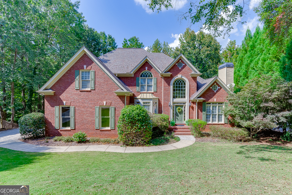 Welcome to this beautifully appointed 2-story home featuring a brick front, full finished basement, and serene wooded backdrop. Inside, hardwood flooring flows throughout the main level and upstairs hallway, complemented by brand-new carpet in the bedrooms. The gourmet kitchen is a chef's dream with granite countertops, stainless steel appliances, a custom-designed island, and a walk-in pantry with a custom shelving system. A keeping room with a two-sided fireplace seamlessly connects to the inviting family room, creating the perfect setting for gatherings. The oversized primary suite is conveniently located on the main level and offers a fireside sitting area-ideal for an office or quiet retreat. The updated spa-like primary bath showcases dual vanities and an enlarged, custom-tiled shower. Upstairs, one secondary bedroom features a private ensuite with hallway access, while two additional bedrooms share a Jack-and-Jill bath, each with separate sink vanities. The terrace level is partially finished and designed for entertaining, complete with a custom kitchenette/bar, ensuite bedroom with a sitting room, and an extended patio overlooking the wooded lot. The unfinished section of the lower level offers ample storage space and workshop area. Additional highlights include a newer Lennox A/C unit on the main level, an active neighborhood association, and a prime location near the Chattahoochee River trails, schools, shopping, and dining. This home effortlessly combines luxury, comfort, and convenience-don't miss the chance to make it yours!