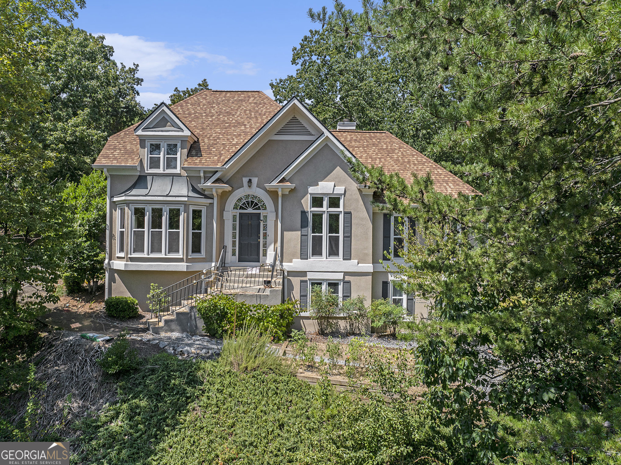 Nestled high on a hill, this home offers unmatched privacy and panoramic views. A long private driveway provides a grand sense of arrival while setting the home apart as a true retreat. Hardcoat Stucco 5-Bedroom, 4-Bath Home with primary suite and secondary bedroom on the main level in the sought-after swim/tennis Highland Pointe community and award-winning East Cobb schools. The main level features a two-story foyer flanked by the dining room and a guest bedroom/office with access to a full bath. The spacious eat-in kitchen opens to the two-story fireside family room with direct access to the backyard patio. The large primary suite, featuring two closets and an ensuite bath, completes the main level. Upstairs you'll find two generous bedrooms that share a renovated full bath. The terrace level offers an additional bedroom, a full bath, and a steam room. Recent updates include: roof (2022), two newer AC compressors (2019 & 2022), water heater (2023), and newer windows. The garage is equipped with a Tesla charging station. The private terraced backyard is perfect for peaceful enjoyment or gardening. Highland Pointe is part of the top-rated East Cobb school district, including Davis Elementary, Mabry Middle, and Lassiter High School. Community amenities include an Olympic-size swimming pool, kiddie pool, clubhouse, four tennis courts with pavilion, two scenic lakes, playground, picnic area, fitness center, sauna, and miles of hiking trails, basketball court, and all-purpose sports field.