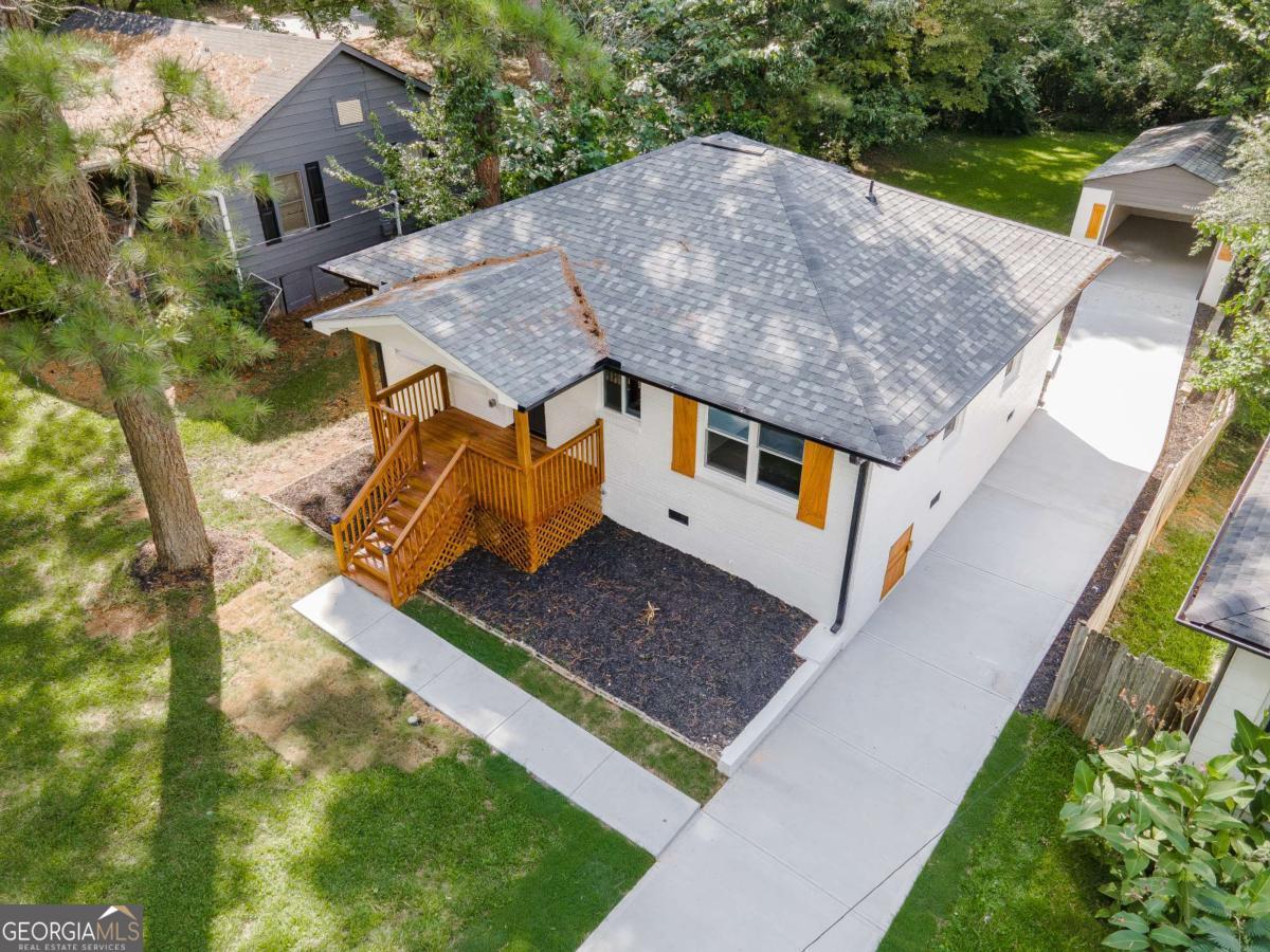 Welcome to this beautifully remodeled brick ranch that seamlessly blends modern design with classic appeal. From the moment you arrive, the stained, covered rocking chair front porch invites you to slow down and enjoy the charm of this thoughtfully updated home. Step inside to find gleaming hardwood floors and an open concept family room featuring a custom modern lighted accent wall, corner shelving, and an electric fireplace that sets the tone for cozy evenings and stylish living. The adjoining kitchen is a true showstopper boasting stainless steel appliances including a sleek vent hood, and a dramatic marble-inspired tile backsplash that extends from counter to ceiling. Sleek cabinetry and quartz countertops deliver a clean, modern aesthetic with just the right touch of traditional warmth. The primary suite features a beautifully updated bath with vertical subway tile. A trendy yet timeless design choice. Two additional secondary bedrooms and another full bath offer ample space, all updated with contemporary vanities, fixtures, and finishes. Outside, enjoy the new deck and extended concrete pad, perfect for parking or entertaining with wooded and private views. A detached garage offers even more storage and flexibility. With no HOA, you'll enjoy the freedom to personalize your property as you see fit. Conveniently located near major highways, healthcare, top-rated schools, dining, shopping, and year-round entertainment. Just minutes from Mercedes-Benz Stadium, and Hartsfield-Jackson ATL Airport. This home checks every box for comfort, style, and location. Move-in ready and waiting for you!