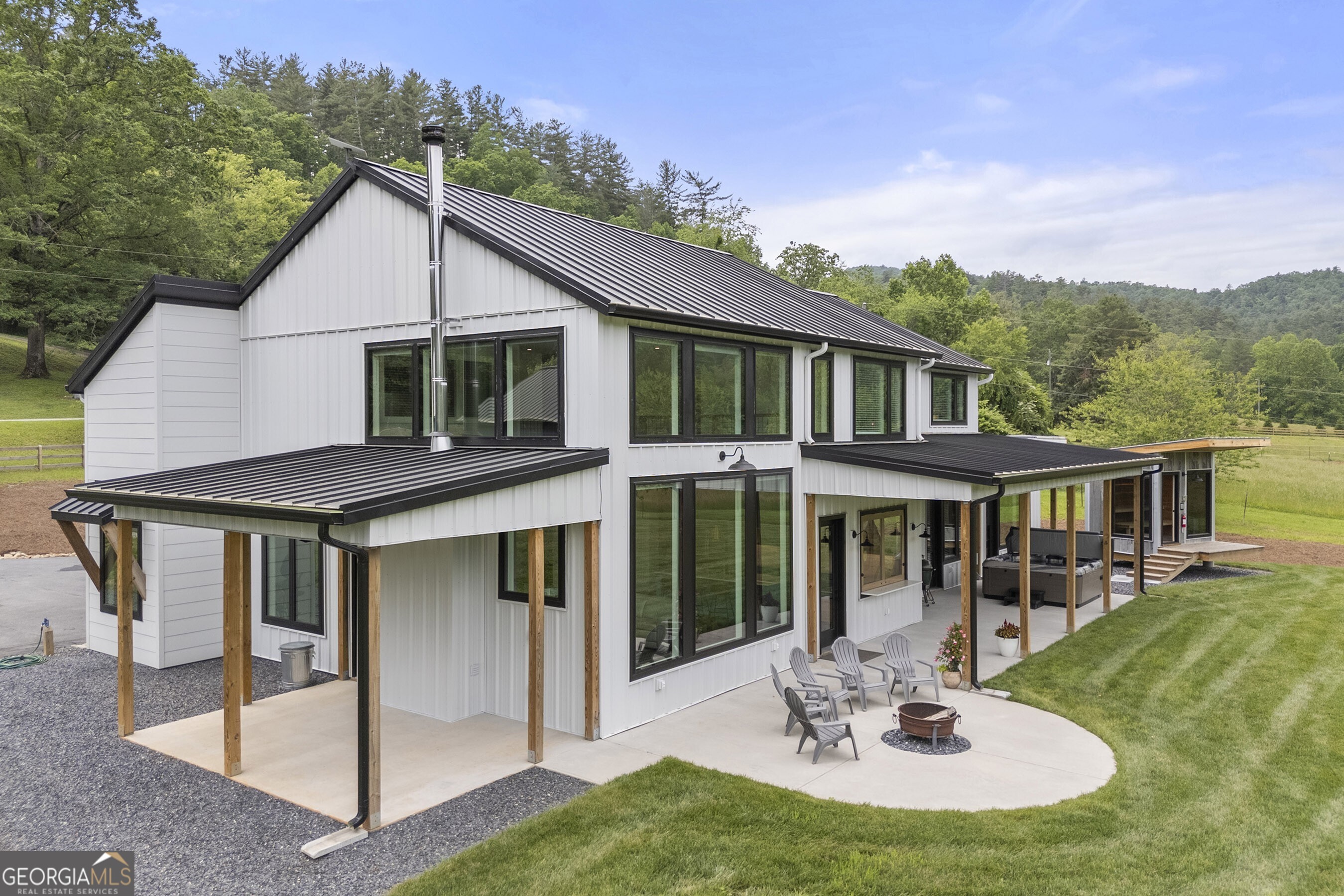 Custom-built by the owner with quality and efficiency in mind, this stunning 4-bedroom, 4.5-bath home rests on 4.67 level, beautiful acres with 450 feet of frontage on scenic Tuckaluge Creek. Every detail was thoughtfully designed-from energy-efficient 2x6 exterior walls and spray foam insulation to a standing seam metal roof and durable siding for long-term, low-maintenance living. All of it is backdropped by the breathtaking Warwoman Wildlife Area of the Chattahoochee National Forest, which meets your street and surrounds your views. Inside, enjoy high-end finishes throughout: custom cabinetry and built-ins, quartz countertops, Bosch appliances, and a walk-in pantry with room for a second refrigerator. The spa-like primary suite on the main level features a luxurious bath with dual shower heads, body spray system, walk-in closet, custom built-ins, and private outdoor access where a freestanding sauna and hot tub await. Additional bedrooms and a bonus media/living room are upstairs-each offering its own mountain view. The oversized three-car attached garage includes 14' ceilings, a 12'x12' RV bay with dedicated power, water, and septic hookups, plus insulated walls and doors. A separate, climate-controlled gym and office connect to both the garage and exterior. Generac transfer switches are in place, ready for generator installation. Bonus space continues in the 725 sq ft insulated shop with a half bath, its own 2-bedroom septic system, and a floor system prepped for second-story expansion. A covered shed adds even more flexibility. Craftsmanship, comfort, and capability-your mountain homestead awaits.