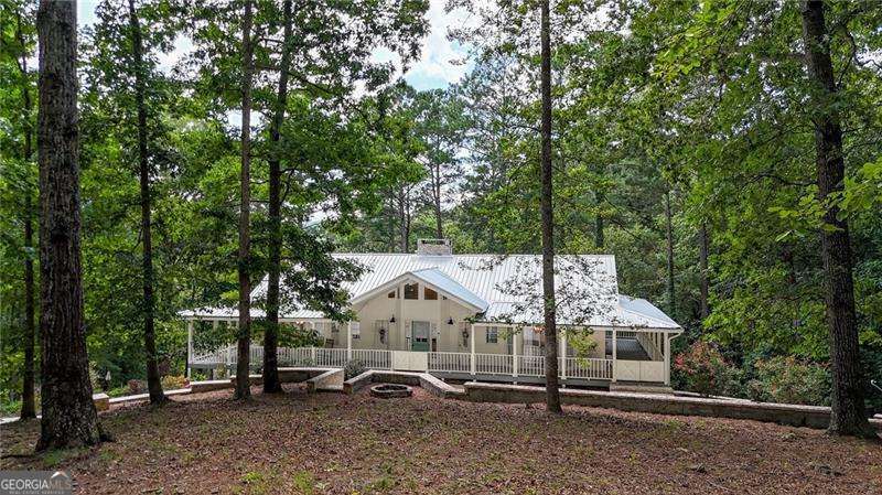 Escape to your own private oasis on 5 acres, complete with stunning water views and tranquility. This exquisitely renovated home is designed for seamless indoor-outdoor living, featuring double wrap-around rocking chair porches perfect for enjoying your serene surroundings. Inside, a grand open foyer welcomes you with gleaming hardwoods and soaring cathedral ceilings. An impressive double-sided gas fireplace connects the main living spaces, creating a warm and inviting atmosphere. The heart of the home is the gorgeous custom kitchen, boasting a custom-built island, quartz countertops, a farmhouse sink, and elegant gold accents. Floor-to-ceiling sliding glass doors in the spacious family room provide a captivating view of the pond. The oversized primary bedroom includes high ceilings, Big Windows & offers direct access to the wrap-around porch, while the en-suite bathroom provides a luxurious escape with double vanities, a separate shower, and an oversized Jacuzzi tub. The secondary bedroom include en-suite bathroom with shower/tub combo. Laundry/mud room is on the main level. Downstairs, a secondary living room with a masonry fireplace offers a cozy retreat and ample space for a man cave, game room, etc. The lower level also features a third bedroom with its own private porch overlooking the pond, A full bathroom, a dedicated office nook, and a tandem garage with space for up to three vehicles. Outside, the double driveway has plenty of parking. Exterior includes a storage shed, fenced in yard and has a large, cleared lot ready for a barn, shop, pasture, or your custom build. Plenty of room for RV, and toys.