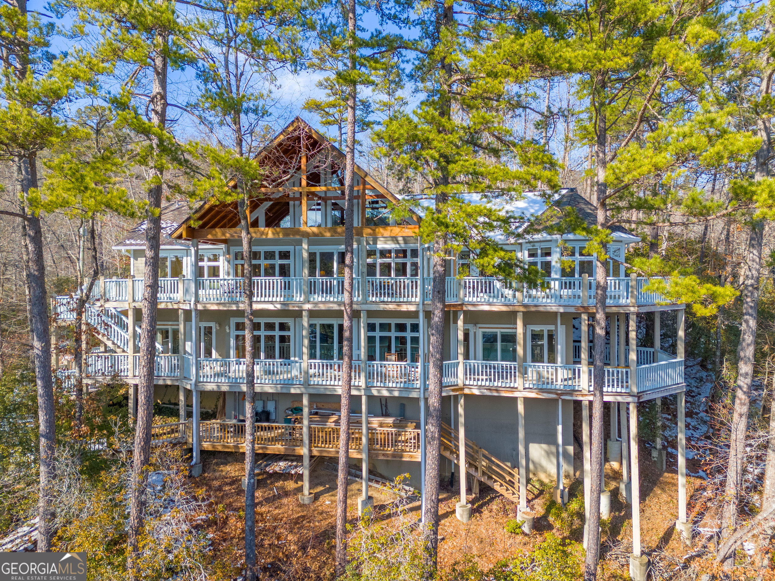 Natural boulders and a timber framed carport introduce this 4 BR/3.5ba Lake Burton home with an open great room, vaulted ceiling and exposed beams, masonry stone fireplace, hickory flooring, reclaimed heart pine wet bar, doors and trim. Kitchen has custom Ash cabinets, granite countertops, two double sinks and breakfast bar with access to wrap around porch with lake views. The master bedroom suite offers a sitting room with turret ceiling and master bath. A guest wing includes a bedroom with full bath and a nearby laundry room and 1/2 bath. A heart pine banister leads to the terrace level family room with masonry stone fireplace, second kitchen, two additional bedrooms, full bath, and a dream workshop/garage. Cart path to 2 stall boathouse.