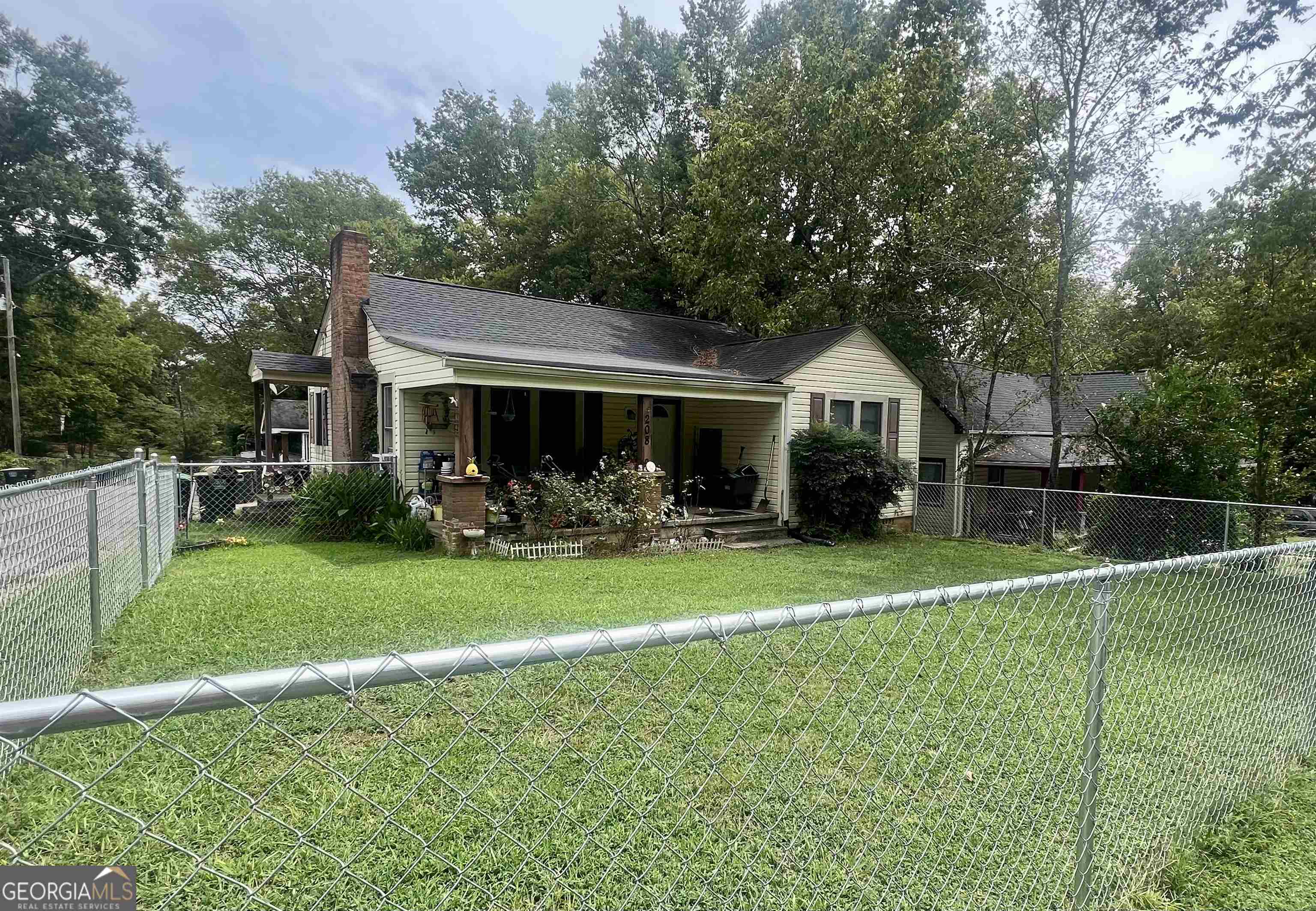 This charming cottage boasts two bedrooms and one bathroom. Adjacent to the bedrooms, an additional room presents versatile possibilities, whether it's a productive home office or an extra bedroom. The heart of the cottage is graced by a welcoming fireplace, complete with gas logs that provide warmth and ambiance on chilly evenings. The open living area creates a sense of unity, seamlessly connecting the living space to the kitchen and dining area. No matter the season, comfort ensured with central heating and air conditioning, allowing for a cozy atmosphere year-round. Stepping outside, the cottage reveals a delightful surprise-a fully fenced yard that offers privacy and a safe haven for outside activity. Sit on the large covered front porch and sip leisurely on your coffee. The yard provides an extension of the living space.