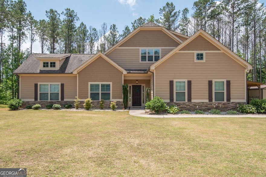 Come visit this beautiful Craftsman Style home with lots of light and windows. Amazingly, the huge, undeveloped parcel located behind the property is owned by the county and NOT buildable, i.e. no neighbors behind you- a rare statement anywhere anymore. But the true magic happens when you walk into your nearly-new home. A large primary bedroom is conveniently split from the other 2 bedrooms on the main floor with a window in the hallway to your 2nd and 3rd bedrooms, also not so widely found, and a large ensuite bedroom upstairs with full bath. This space is perfect for teens or guests, hobbies, or work from home. All the bedrooms are of great size with bigger closets. The family room is very spacious and has a gas log fireplace. The eat-in kitchen is huge with lots of counter space, filled with cabinets, overlooking a peaceful, wooded backyard. Outside, you will find a covered 27' X 21' pole barn that is perfect for recreational vehicles. There is also a 20' X 10' outbuilding for additional yard toys or lawn mowers. All this in a NON-HOA, quiet and serene subdivision. Newnan is 5 minutes away and Ashley Park Shopping just 15 minutes. Outdoor enthusiasts will love the easy 5-minute drive to Brown's Mill Historic Battlefield for hiking and exploration, or 30 minutes to Chattahoochee Bend State Park for some kayaking and camping. 10 minutes to I-85. Qualifies for USDA 100% Loan program. Call today to see this amazing house you can make your new home.   !Please! !Turn! !Off! !Lights!