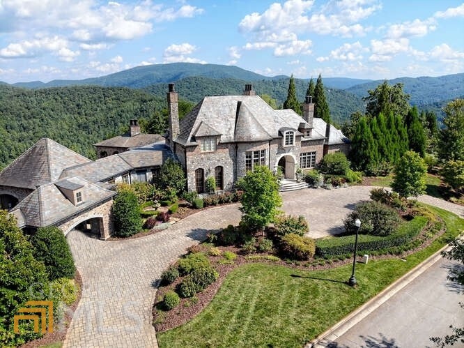An unprecedented masterpiece showcased on a North Georgia mountaintop overlooking the emerald green waters of Lake Burton, the cerulean layers of the Blue Ridge mountains as far as the eye can see, and the perfectly manicured fairways of Waterfall Golf Course. Located on two lots within the prestigious Waterfall at Lake Burton, this extraordinary custom home is immaculately adorned with exceptional finishes and furnishings. 6 bedrooms including two master suites and a guest house, massive his and hers closets, 6.3 unique bathrooms, 7 fireplaces with one-of-a-kind hand-carved mantles, stunning entertainer s kitchen with adjoining butler s kitchen, hearth room, formal living room, two-story library with mahogany French doors and custom stained glassed ceiling, formal dining room, two custom marble-top bar areas, game area, wine cellar with tasting area, sun room overlooking the mountains, movie theater, two laundry rooms, two offices, craft room, elevator, sauna, Koi pond with waterfall, wading pool/hot tub. Custom circle drive with landscape pavers and breezeway to 4 car garage. 2,000+ sq ft of storage space, safe room, generator, and camera system throughout interior and exterior that can be accessed from anywhere. EXQUISITE!!! Please view the virtual tour for additional details.