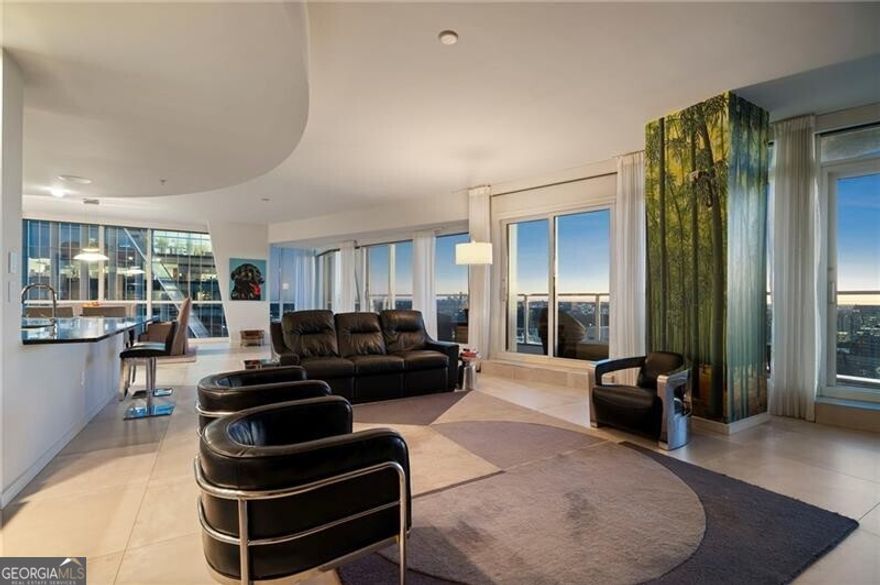 A rare offering in highly sought-after Terminus - one of only three residences with this sexy and coveted floor plan - this impressive corner unit embodies elevated Buckhead living with its expansive layout and nearly 360-degree skyline views from the 3 separate terraces. An entertainer's dream, the open-concept living area features a fireside great room and a sleek bar complete with Sub-Zero wine storage. The adjoining dining and media rooms flow seamlessly into a gourmet kitchen outfitted with top-of-the-line appliances, including Sub-Zero refrigeration, Wolf gas range and warming drawer, and a convenient breakfast bar. A separate catering entrance off the kitchen makes hosting effortless. Step outside to the oversized, covered terrace and take in breathtaking views of both Buckhead and Downtown - the perfect backdrop for dining or entertaining al fresco. Privately situated, the luxurious primary suite with Venetian plaster walls offers a tranquil retreat with a sitting area framed by floor-to-ceiling corner windows, a private covered terrace with views of Stone Mountain and Buckhead, and an expansive custom walk-in closet with a built-in safe. The spa-inspired bath showcases dual vanities and water closets, a soaking tub, and a frameless glass shower - all positioned to capture the home's extraordinary vistas. Two additional guest suites, each with ensuite baths, share a third balcony and are thoughtfully placed off the foyer for privacy. Additional highlights include Famosa Italian tile throughout, motorized shades throughout, leak defense water system, Toto toilets, and a fully integrated Lutron and Control4 smart home system and a 1/2 bathroom. Two deeded, covered parking spaces complete this exceptional offering. Perfectly positioned at Terminus, just steps from Buckhead's finest dining, shopping, and MARTA access.