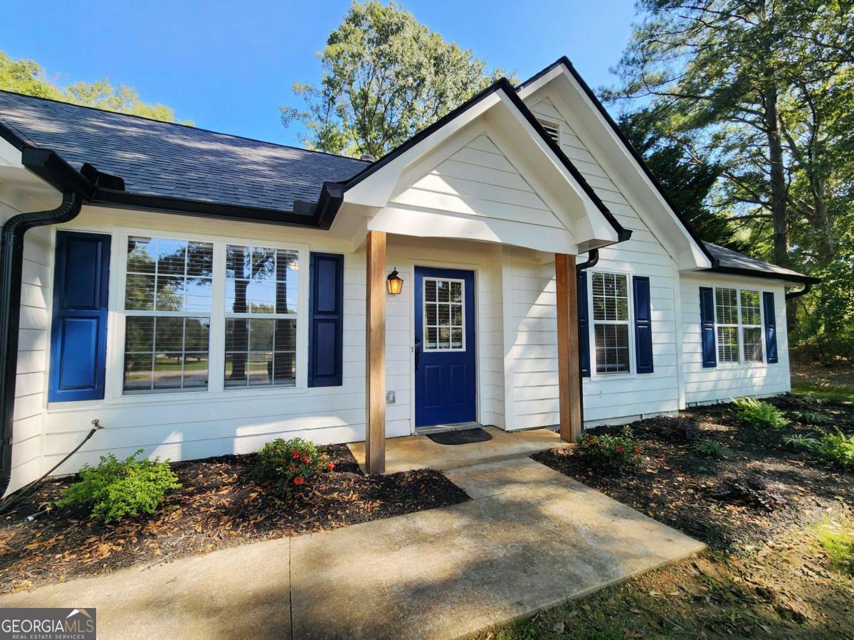 Welcome to this fully updated stepless ranch in a prime Conyers location with a NEW ROOF! Conveniently situated near Downtown Conyers, Mall at Stonecrest, reputable schools, and an abundance of grocery stores, dining options, and year-round entertainment. With easy access to major highways, commuting is a breeze. Fresh curb appeal greets you with a stylish pop of contrasting color, a two-car separate door garage, and an extended parking pad offering plenty of space and privacy. Step inside to a spacious vaulted family room with a cozy fireplace, perfect for relaxing or gathering with friends and family. FRESHLY PAINTED INTERIOR AND NEWER FURNACE. The open dining area flows seamlessly into the galley-style kitchen, complete with granite countertops, stainless steel appliances, and a functional layout for everyday living. A laundry room with built-in storage cabinets adds convenience. The primary suite features a tray ceiling, double closets, and marble-like tile in the walk-in shower. Two additional bedrooms and another full bathroom provide plenty of space for family, guests, or a home office. The spacious backyard boasts mature shade trees, creating a private and serene setting where you can design your dream outdoor space. With no HOA restrictions, you have the freedom to customize the property to fit your lifestyle. This move-in-ready home blends modern updates, a fantastic location, and ultimate convenience, perfect for homeowners or investors alike!