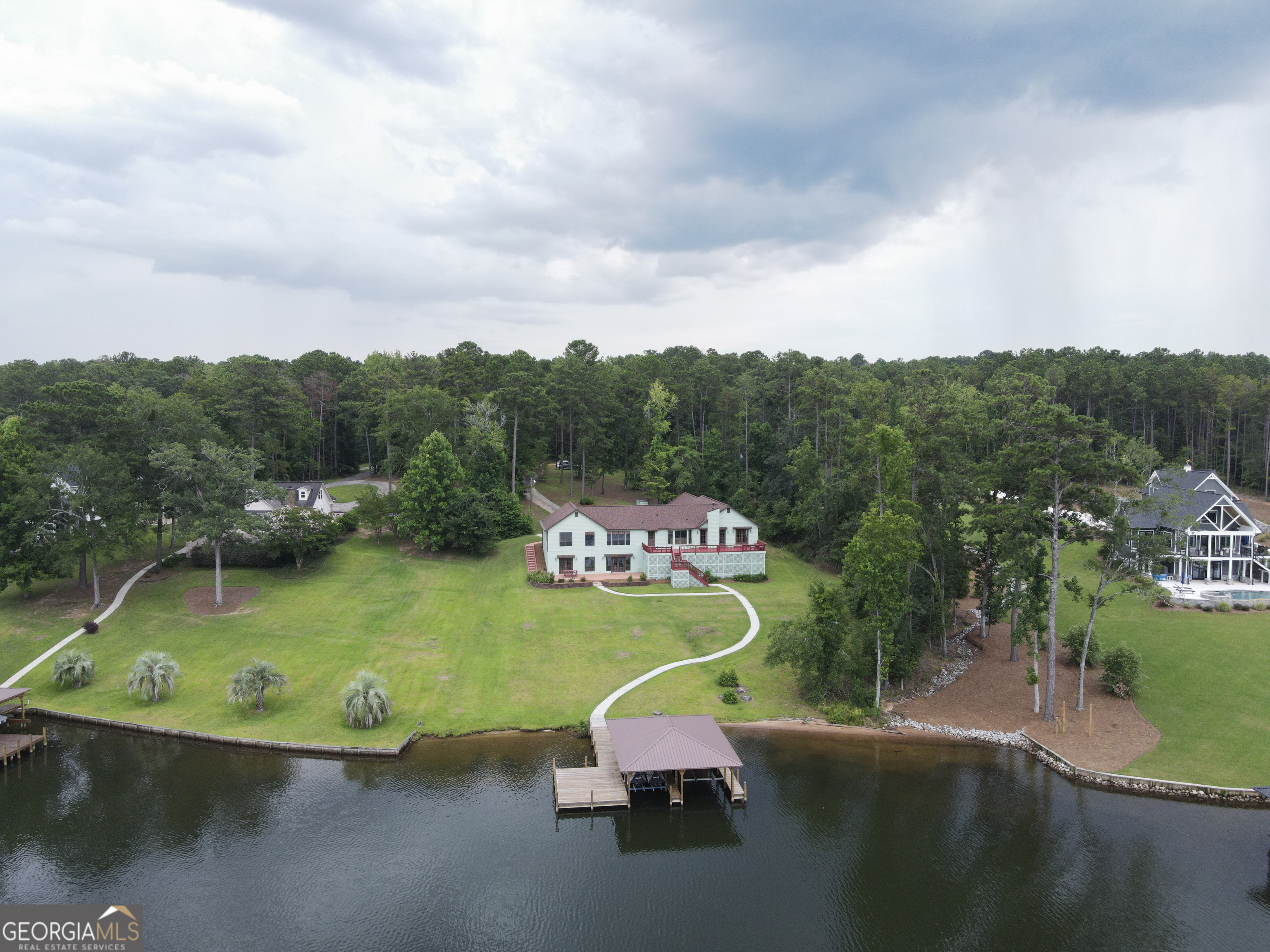 Looking for a Lake Sinclair home with acreage, privacy, a double boathouse, and located in Baldwin County in a very desirable area of the lake and 10 miles to downtown Milledgeville? Well look no further! This 4400+ square foot home is located on 3.65 acres, features 5 bedrooms (2 of which are ensuites and located on the main floor) and 4.5 baths, an office, 2 full kitchens, 2 great rooms, 2 laundry rooms, and a wood burning fireplace. Moving to the outside you will find a massive deck that is almost half the length of the home and has built-in seating and a lower patio. There is a paved partial driveway, a 3-car garage, and paved walkways to the dock. Speaking of docks; this dock is built to stand the test of time! Dock was built with 2000 PSI pressure treated lumber and the 6x6 posts that supports the roof are anchored in the bottom of the lake. No wind concerns here! This lot has over 100 ft of water frontage, a sandy beach area and a double boathouse with a max dock on some of the clearest water on Sinclair. There is beautiful flagstone throughout the home and a great front porch with 2 entrances. This home could easy be turned into a duplex and possibly another home built on the acreage. Lots of possibilities! Don't miss this one! Call to schedule a showing today!