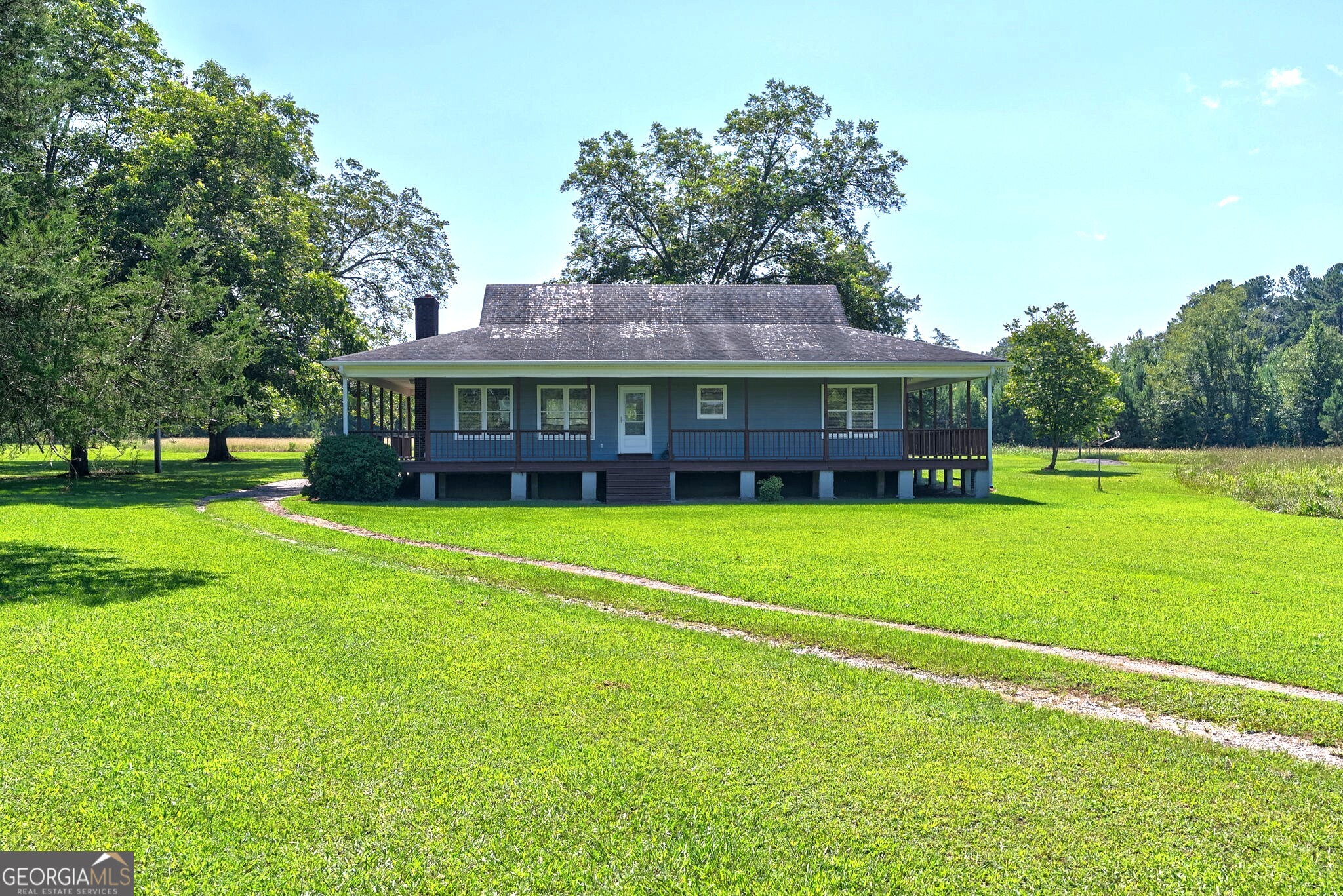 Welcome to your private country escape. Nestled on 65 sprawling acres, this charming farmhouse features a wraparound porch perfect for enjoying sunsets, stargazing, and soaking in the peaceful sounds of nature. Built in 2000, this 3-bedroom, 2-bath beautifully maintained home offers lots of rustic charm with modern comforts. The expansive porch wraps around all four sides providing unlimited panoramic views. Inside, you will find an open concept living area with a wood burning fireplace, spacious kitchen with island, dining area, and gorgeous hardwood floors throughout. The master suite boasts tray ceilings, walk-in closet, and private bath. Out back, you'll find a detached garage for vehicles, equipment, or even a workshop and ample storage space. Located just 8 miles from Downtown Greensboro or a quick drive to Lake Oconee, this secluded property offers the perfect balance of rural tranquility and urban conveniences. Prime dove/deer field is hunt-ready or use this cleared section for your own recreational enjoyment. Don't miss this opportunity to own a slice of country paradise on 65 acres offering ample privacy, room to expand, or to just explore and relax. Schedule your showing today!