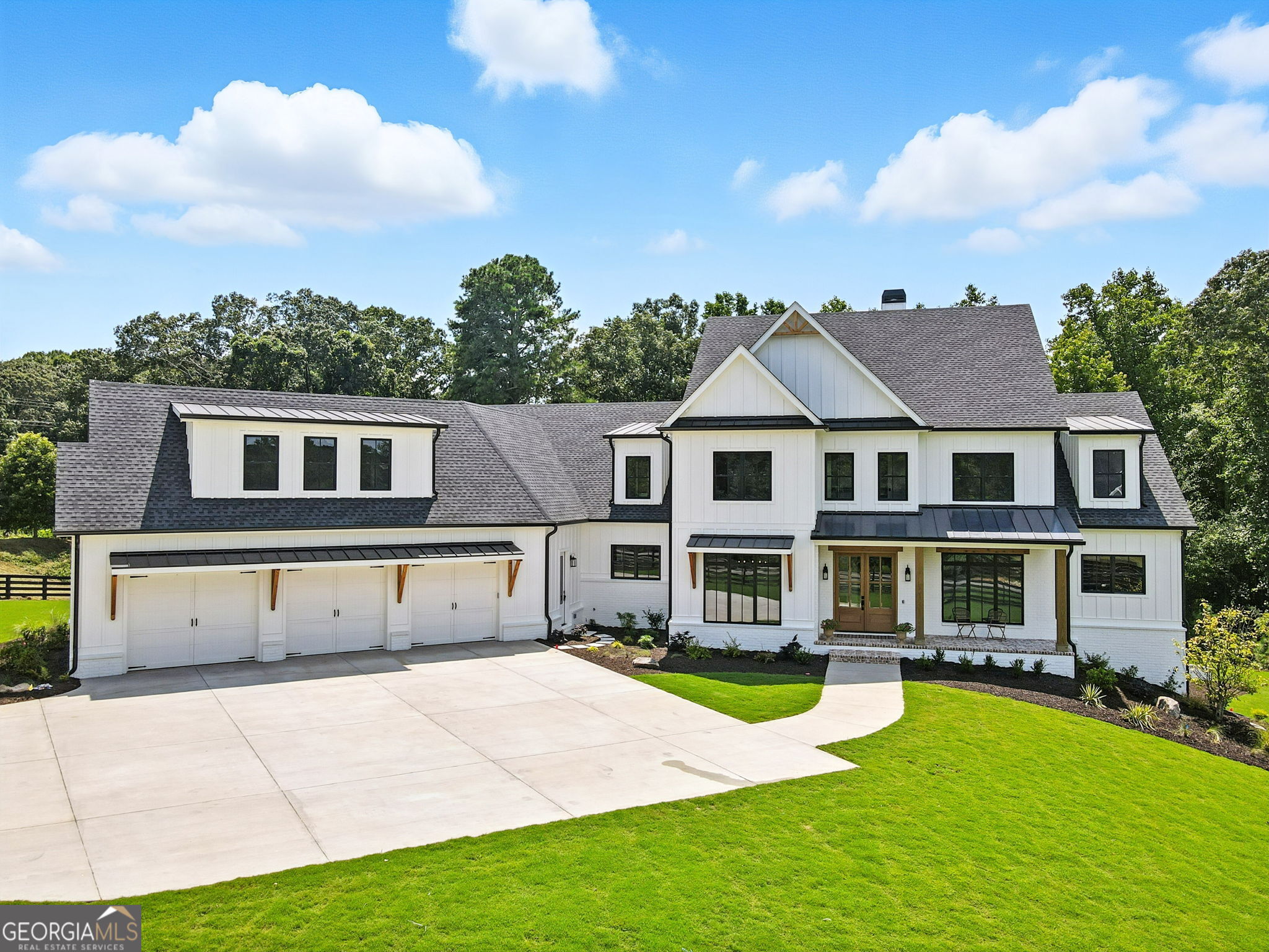 Exceptional custom-built farmhouse featuring six bedrooms, five and a half bathrooms spread across two spacious and thoughtfully designed levels. The main level includes three bedrooms, each with its own private ensuite, while the upper level offers a secondary primary suite or bonus room with an ensuite bath, a built-in kitchenette, and two dedicated computer workspaces-ideal for flexible living needs. A large, unfinished basement is stubbed for a full kitchen, a full bathroom, and a half bath, making it perfect for a future in-law suite or separate apartment. It also includes a built-in vault/panic room for added security. The chef's kitchen is a standout, featuring a Wolf 48" gas range with six burners and a griddle, a Sub-Zero 48" panel-ready refrigerator, Cove dishwasher, microwave drawer, a custom plastered hood accented with white oak, and high-end Delta plumbing fixtures. Artisan cabinetry and quartz countertops complement the space, white oak flooring flows throughout the main living areas and bedrooms. The bonus room is finished with Berber carpet. Custom touches include white oak beams with a shiplap ceiling in the great room, coffered ceilings in the dining area, white oak beam details in the office, wrought iron stair railings with oak treads, designer tile work in all bathrooms and laundry rooms, and custom built-ins in all closets. There are three laundry areas: a luxury main-level laundry room with a built-in dog wash, a secondary laundry upstairs, and a private laundry in the primary suite. A walk-in attic provides easy access to HVAC systems. The home is equipped with a Trane 17-SEER variable-speed HVAC system on the main level and a separate system for the upper level, as well as a tankless water heater. Exterior features include board and batten cement siding on the main and upper levels, painted brick on the basement level, a front porch with brick pavers, and a rear deck with fireplace, Trex-style decking, and a gas grill stub. The property is finished with Sierra Pacific aluminum-clad windows and doors, entry columns wired for lighting, four-board fencing on three sides to match the subdivision, and a fully irrigated, professionally landscaped yard. A natural gas line is stubbed for a generator, and the backyard is designed with space for a future pool. Additional features include a three-car garage and an oversized parking pad. This home offers a rare combination of luxury, flexibility, and quality craftsmanship, making it an ideal fit for growing families, multigenerational households, or buyers who appreciate elevated design and long-term versatility.