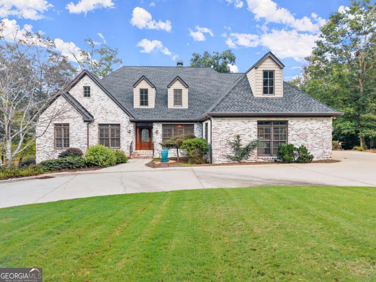 Welcome to this rare stretch of north Lake Lanier shoreline, where the grass rolls gently to the water's edge and the double-slip dock sits just steps from the back porch. Here, the water is deep and wide, and begging to be enjoyed. This classic, yet refreshed, brick residence is bathed in sunshine and effortless lakefront luxury. Wide water views greet you from nearly every room, grounding the home in the serenity of Lake Lanier. Inside, light-filled gathering spaces balance comfort with quiet sophistication. A classic craftsman entry leads into a welcoming foyer, flanked by an office and formal dining room with refined wall and ceiling details. Lanier's sparkling waters reflect off the great room walls. The kitchen-fitted with granite, stainless appliances, and a central island-flows seamlessly into rooms designed for connection: a keeping room warmed by a double-sided fireplace, an enclosed sunroom for morning coffee, and a screened porch that brings the outdoors in. The main-level primary suite is a private retreat, offering tranquil lake views, screened porch access, and a spa-like bath that invites pause. Upstairs, two generous suites and a lofted common area provide both comfort and privacy. The spacious, walk-in, expandable attic offers versatile possibilities-whether for storage, future teen retreat, an additional study, or craft room. Meanwhile, the terrace level opens an entirely new dimension of living. With its own kitchen, private entrance, theater, game room, and vast living area, this space is ideal for multi-generational living or an income-producing retreat-all without sacrificing the sense of home. Freshly updated, move-in ready, and defined by its ease of living. This residence is not just a lake house-it is a lifestyle, where weekends spill into weeks, and the water becomes a daily backdrop to life well-lived. Set in the desired North Hall school district, the property offers an exceptional location by lake or land.
