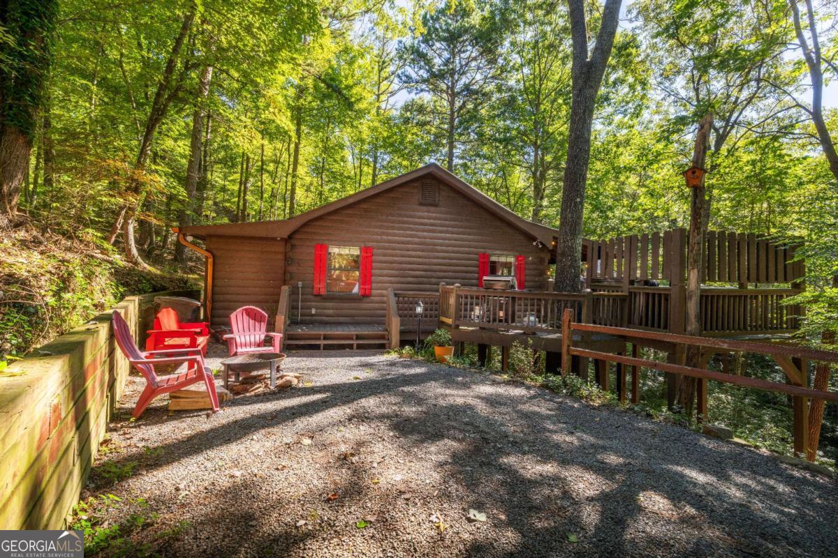 Welcome to your quintessential retreat in the woods! Tucked conveniently between Ellijay and Blue Ridge, this quaint Cherry Log cabin offers easy access and ample parking space, surrounded by the tranquility of peaceful nature. Step onto the wrap-around porch and take in the breathtaking scenery or relax under the stars in the hot tub. Inside, the cabin exudes charm with wide plank real hardwood floors, a beautifully updated kitchen with modern appliances, and a cozy gas stove. Currently a successful rental, this cabin presents a fantastic investment opportunity. It's also perfect as a quick getaway to the mountains or a second home. Coming fully furnished, all you need to bring is your toothbrush! Embrace the serenity and charm of this delightful cabin and make it yours today.