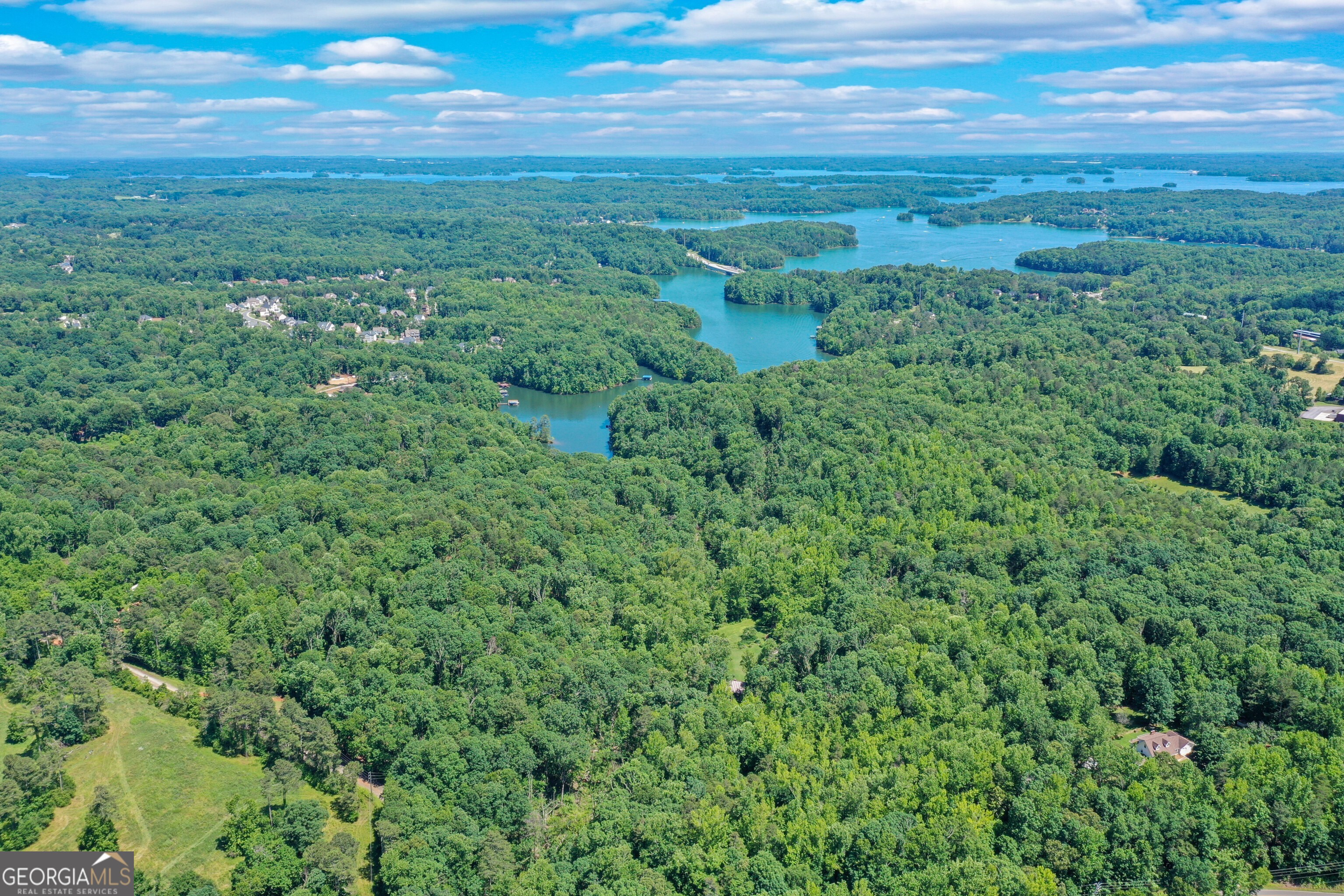 This stunning Lake Lanier property is truly one of a kind, offering 34 acres of pristine land and four (4) private docks! Whether you envision an amazing family retreat, gorgeous private homesite, an exclusive residential enclave, or a haven for outdoor recreation, the possibilities are as vast as the imagination itself. Imagine a place on Lake Lanier beautiful with lush landscape, a place so tranquil and peaceful with the gentle melody of a nearby river, its waters cascading with a soothing rhythm. As you enter the property, close your eyes, and for a fleeting moment, you may believe you've been transported to the misty heights of the North Georgia mountains, where time slows, and worries fade. Come experience the breathtaking allure of Burruss Mill Falls, a sanctuary where the echoes of history blend harmoniously with the splendor of Lake Lanier. Tucked away in the picturesque landscape of North Georgia, this estate is a testament to timeless elegance, boasting a 19th-century "Salt Box" Grist Mill that exudes the nostalgic charm of New England architecture. Dating back to the 1800's, the grist mill has been artfully repurposed into a residence, and most recently into a wedding venue. Six Mile Creek winds its way through the verdant surroundings, adorned with ancient Carolina Hemlock trees, native Azaleas, towering White Pines, majestic Magnolias, and a diverse array of indigenous flora. A graceful waterfall cascades into a peaceful oasis where Six Mile Creek meets Lake Lanier. The sprawling shoreline, framed by Mountain Laurel, extends gracefully into the beautiful blue-green waters only the south end of Lake Lanier has to offer. The Grist Mill stands as a captivating focal point, offering boundless opportunities, while the surrounding grounds provide an expansive canvas for a myriad of leisure activities and luxurious amenities. With the option of using the mill as a temporary residence while building your dream home, this provides a practical and charming idea offering a unique living experience amidst the natural surroundings of the property. This unique property is positioned in a coveted south lake location, just three miles east of Georgia 400 and a mere hour drive from Atlanta. This property offers unparalleled convenience and endless potential. The seller is open to dividing the property into larger tracts. This one is sure to impress, don't miss it!