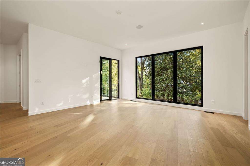 Step into the realm of modern luxury with this stunning ultra-modern new construction masterpiece located in the heart of Buckhead, meticulously designed by the renowned architectural designer Jeffrey Baker and featuring interiors by Bellwether Interiors. Enter through the impressive steel pivot door to experience a grand three-story foyer leading into an expansive floor plan. The focal point is an 18-foot porcelain slab fireplace complemented by striking light fixtures, a custom glass and steel floating staircase, and a suspended floor-to-ceiling glass wine rack. Expansive windows flood the spaces with natural light, framing views of the lush backyard oasis. The home opens through stunning 10-foot aluminum doors to reveal your very own retreat that enchants with its resort-like allure. Surrounded by lush greenery, an elevated heated infinity pool with cascading water features invites you to a refreshing sanctuary, while the spacious patio offers relaxation and sunbathing. For chilly winter nights, a bubbling hot tub promises warmth and endless enjoyment. The chef's kitchen is a culinary haven, boasting European custom cabinetry with high-end appliances, including two large volume panel fridges and freezers, and a stunning quartz countertop. Adjacent, a full prep kitchen awaits with four ovens, a panel fridge, a dishwasher, a sink, and a wine fridgeCoa perfect space for private chefs or catering. The primary suite, located on the main level, offers the ultimate escape with a luxurious bath featuring a soaking tub, a glass shower, and a floating double vanity. The carefully curated third level features a private rooftop terrace with a fireplace. Additional amenities include a private fenced-in backyard, built-in speakers, a finished basement with additional rooms, and a three-car garage. Nestled just steps from Phipps Plaza, this home offers a private, secluded feel while providing the luxurious conveniences of Buckhead living. Don't miss the opportunity to claim this exceptional residence, where modern luxury and thoughtful design converge to create an unparalleled living experience.