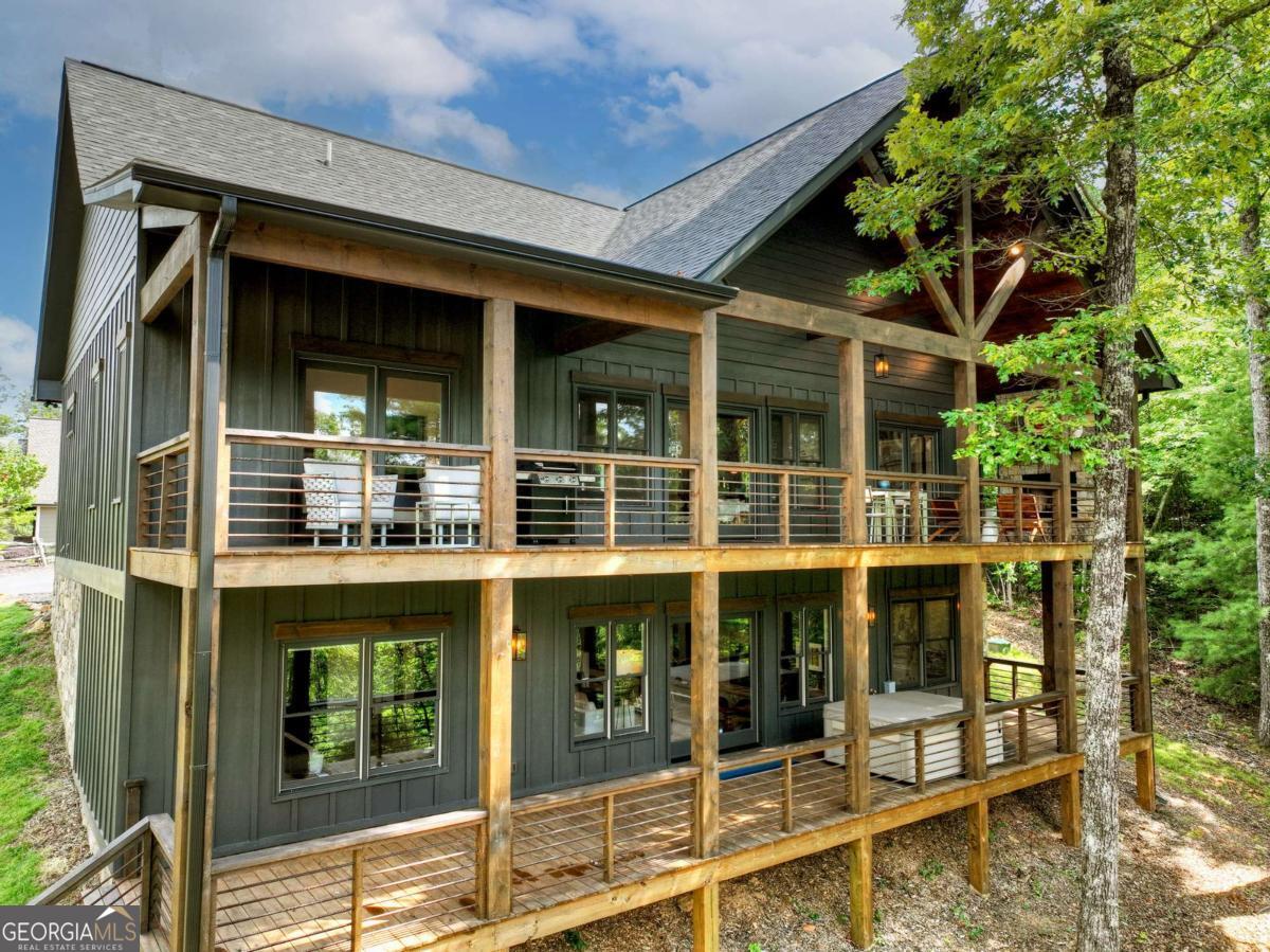 Perched in the prestigious gated community of Staurolite Mountain, just minutes from the heart of Downtown Blue Ridge, 141 Long View Lane offers the perfect balance of refined luxury and mountain charm. This striking contemporary-craftsman residence features all-paved access and a desirable location within a private enclave complete with a community pavilion. Thoughtfully designed across two expansive levels, the home boasts an open-concept layout with seamless indoor-outdoor living. The main level welcomes you with a gourmet kitchen outfitted with premium appliances, custom cabinetry, and a spacious island flowing into a stylish dining area and an inviting living room centered around a sleek contemporary fireplace. French doors open to a sprawling covered deck with its own stone fireplace-perfect for year-round entertaining and enjoying the scenic short-range mountain views. The main level primary suite is a serene retreat, complete with a spa-inspired ensuite featuring a walk-in tile shower, vessel soaking tub, and a custom walk-in closet. Two additional guest bedrooms share a well-appointed luxury bathroom on the main level. The terrace level offers an ideal space for hosting, with a second oversized living area, game room, full wet bar, and two additional bedrooms, along with a full bathroom, large laundry room, and generous storage. Step outside to a walk-out patio and a beautifully landscaped path leading to a custom fire pit area overlooking peaceful vistas. Whether you're seeking a full-time residence or luxury mountain getaway, this home is an exceptional offering in one of Blue Ridge's most desirable gated communities. Select furnishings are available for purchase separately.