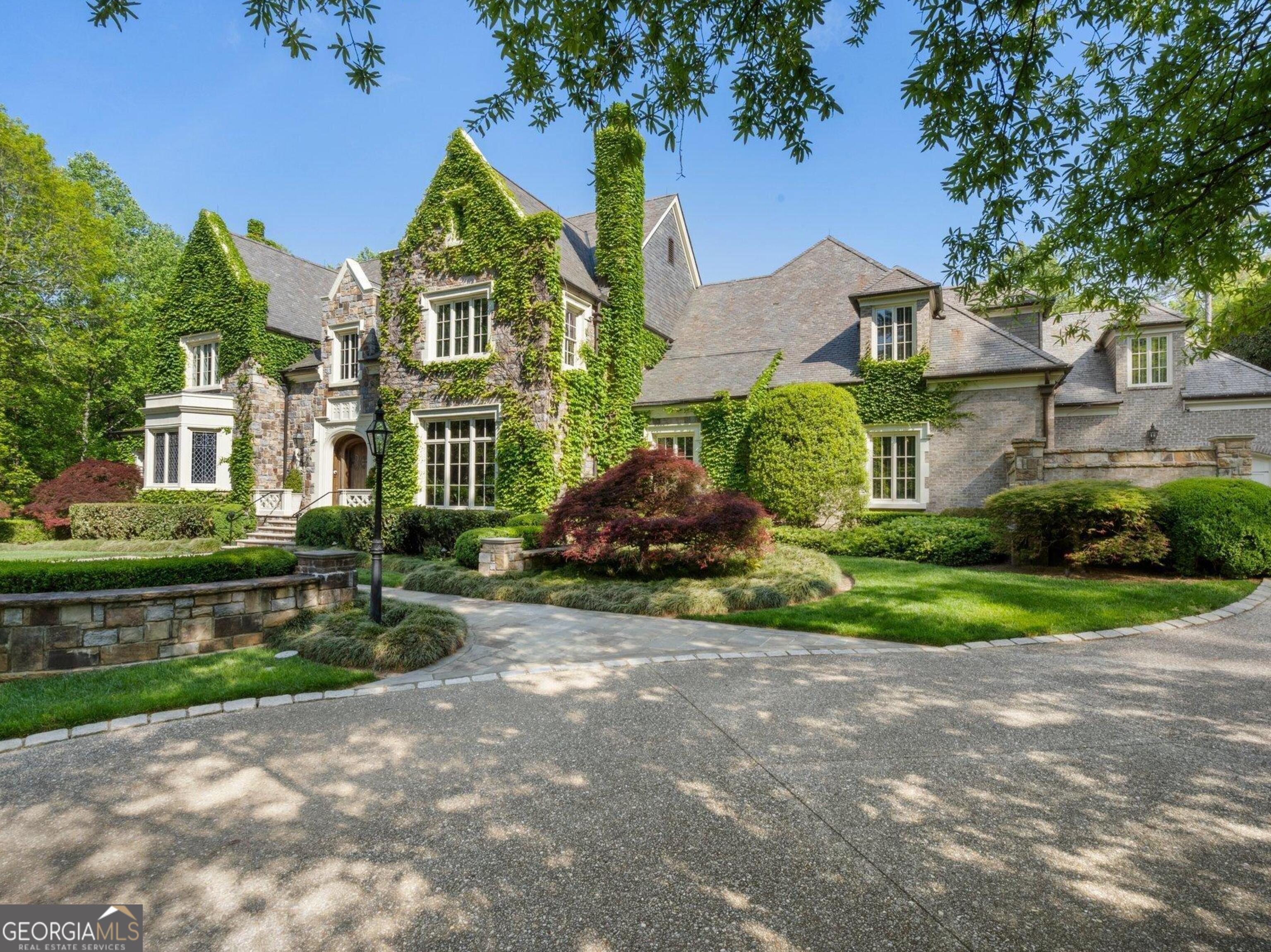 Set on an expansive three-acre private estate in Atlanta's exclusive Paces Ferry neighborhood in Buckhead, this stunning custom stone English manor, designed by renowned architect William T. Baker and built by custom builder McGarity.Timeless elegance combined with modern sophistication. Exceptional value at this price and available now. This gated property set way back from the street with a sweeping drive leading to a meticulously designed motor court and four-car garage, ensuring plenty of parking options. The interiors finishes are a testament to exceptional craftsmanship, beginning with the grand two-story foyer, where oak paneling and marble floors set a luxurious tone. To the left, an elegant study with fireplace provides a refined retreat. To the right, is a formal living room with fireplace or seating area. The heart of the home is the chefs kitchen and separate catering prep kitchen. Featuring two expansive islands clad in marble, professional-grade appliances, and dual pantries - including a butlers pantry - designed to make entertaining seamless. This space flows effortlessly into the spacious family room, complete with soaring vaulted ceilings, a cozy fireplace, and an adjacent sunroom that invites natural light and views of the lush surroundings. A standout feature is the glass conservatory, imported from England, offering a serene space to enjoy the gardens year-round. The main-level primary suite is a private sanctuary, complete with a sitting area, fireplace and overlooking the pool. Two separate generously sized dressing rooms. Upstairs, four additional bedrooms, each with en suite bathrooms, provide ample accommodations for family and guests. A versatile bonus room and an elevator that accesses all three levels add to the homes functionality. Whole house generator, upgraded integrated lighting and security system. The terrace level is designed for recreation and relaxation, boasting a billiards area, full bar, wine cellar, fitness center, sauna, and a state-of-the-art movie theater. Outside, the grounds, envisioned by famed landscape architect John Howard, offer a resort-like experience. Enjoy lush, professionally curated gardens with over 70 specimen Japanese Maples, a sparkling pool with a hot tub, an open-air summer pavilion, and a dedicated play area with playhouse. This 3 acre estate offers unparalleled access to Buckhead premier shopping, dining, and some of the cities top public and private schools. Own a legacy property blending classic sophistication with modern amenities in one of Atlanta's most sought-after locations.