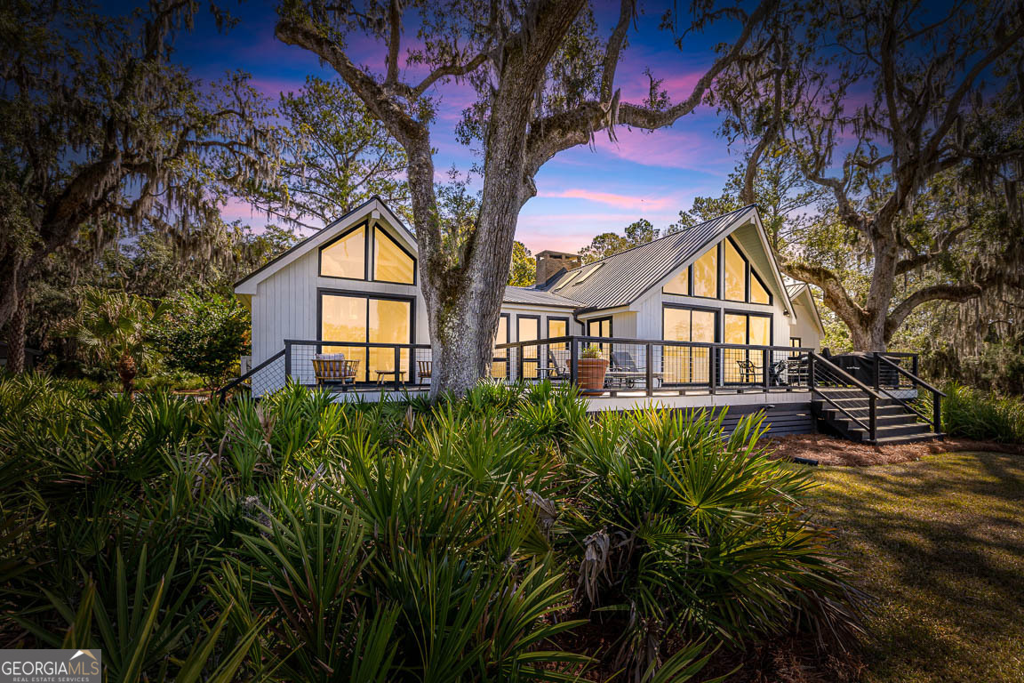 Nestled on a private 4.5-acre lot on St. Simons Island, this secluded retreat offers a rare and tranquil sanctuary with breathtaking marsh and nature views. A private entrance welcomes you across a bridge, guiding you down the long driveway to your own peaceful oasis. As you step inside, a charming brick foyer leads you into the spacious open living area, complete with a cozy wood-burning fireplace and a kitchen with soaring vaulted ceilings that add a sense of grandeur. The kitchen is an entertainer's dream, featuring stainless steel appliances, a warming drawer, and a large island with a propane cooktop, sink, and an eat-in breakfast bar. The space effortlessly flows outdoors to an expansive deck, ideal for enjoying the best of indoor/outdoor living. The main living areas and primary bedroom are adorned with refinished hardwood floors, adding warmth and character. The primary bedroom is a true retreat, featuring vaulted ceilings and a brick-floor sitting area that opens directly onto the large deck. The luxurious ensuite bath is complete with dual vanities, a separate tiled shower with dual shower heads, and a soaking tub, creating a spa-like experience. This home also offers two additional guest bedrooms, 2.5 baths, a formal dining room, and an oversized laundry room. The enormous loft area provides endless possibilities, whether as a fourth bedroom, office, or bonus room. With ample parking options, including a two-car detached garage with extra storage and an additional carport, this home is equipped to meet all your needs including boat and RV parking. Featuring a durable metal roof and three mini-split systems for efficient climate control, this property truly has it all. NO HOA and plenty of room for a hobby farm and pool!!!!