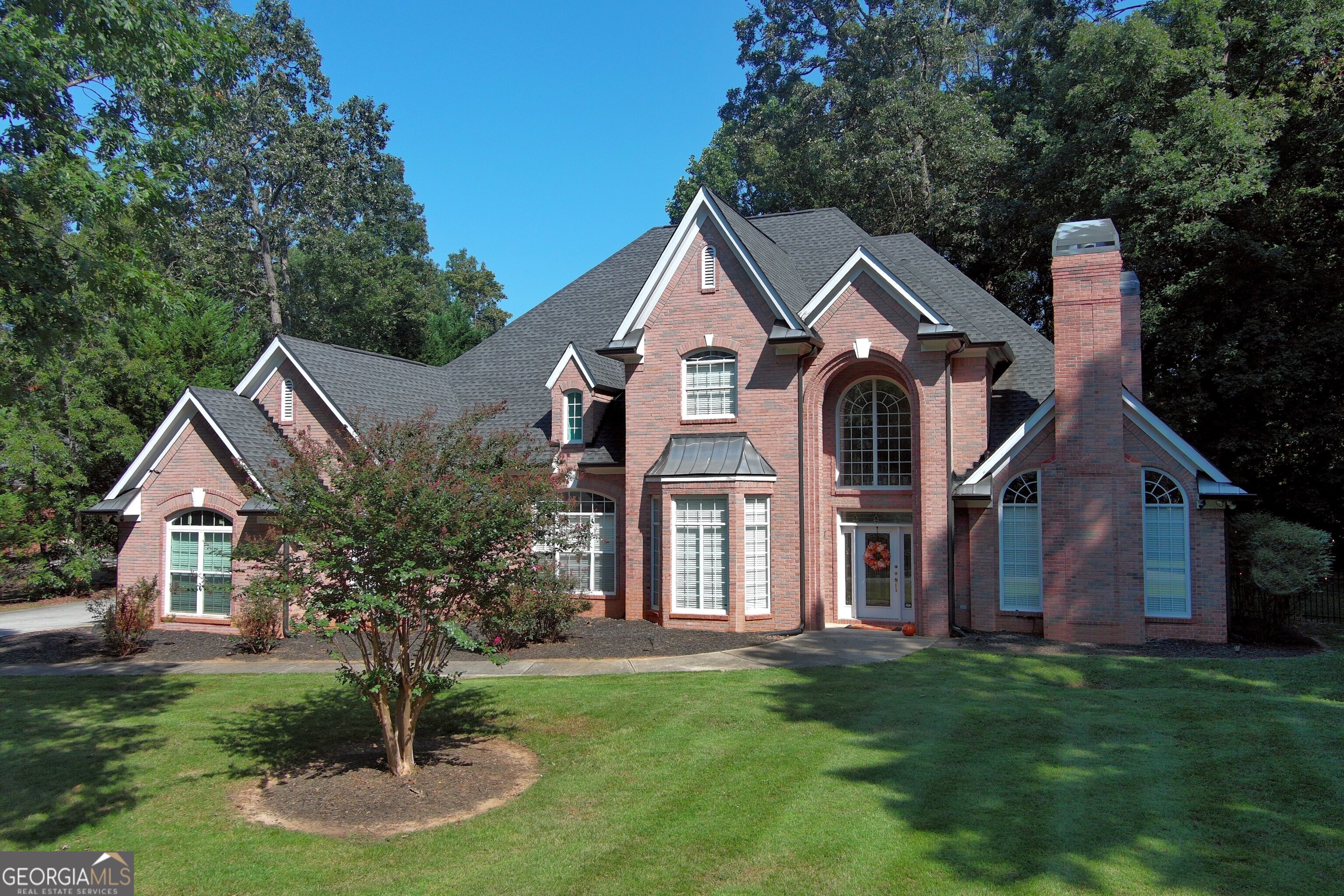 Exquisite Custom Residence in Lake Spivey Country Club. This custom brick home embodies timeless luxury with 5 bedrooms, 3.5 baths, and over 4200 square feet, it overlooks the golf course for a serene, sophisticated lifestyle. Enter through a grand two-story marble foyer with a winding staircase. Formal living and dining rooms accented by tray ceilings, picture molding, and hardwood floors. The family room features a fireplace and wet bar, while a study with built-in bookcases offers quiet retreat. The gourmet kitchen impresses with custom cabinetry, Corian counters, a center island, breakfast bar for four, ceramic backsplash, and wood floors. The main-level master suite is a private haven, complete with sitting area, French doors to the covered patio, and an en-suite bath boasting marble floors, jetted tub, dual vanities, and dressing table. Upstairs, four additional bedrooms, a loft with built-in desk, and walk-in attic provide ample space. Outdoors, enjoy the wrought-iron fenced yard, covered patio with BBQ, and views of the 9th hole. A three-car garage adds convenience. New updated AC unit with warranty.