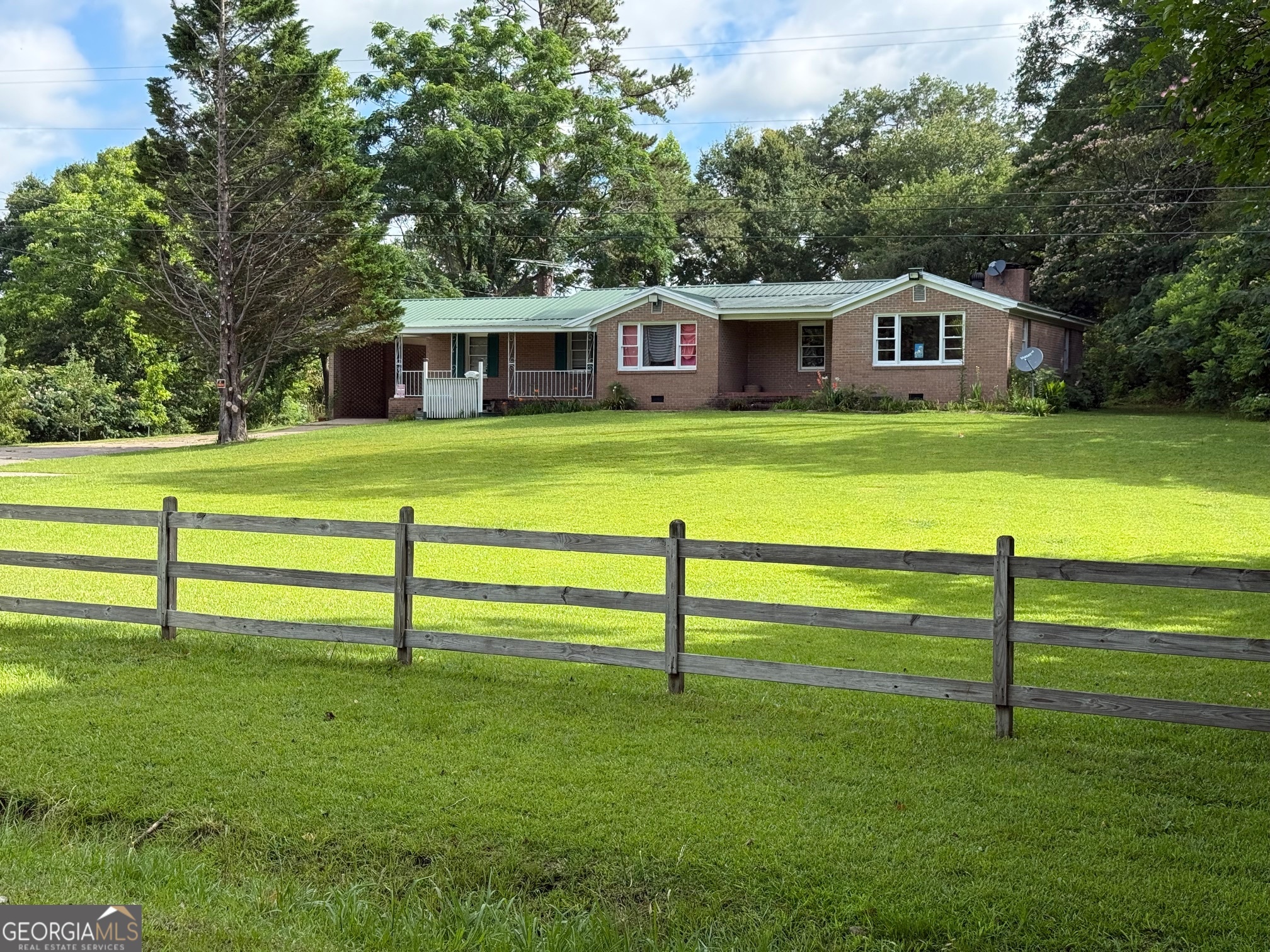 Mini farm dream come true-13.6 fenced acres, 2 ponds, multiple barns, sheds, stables, and a charming brick ranch-all at an unbeatable price! Opportunities like this don't come around often in Meriwether County. This 1954 brick ranch sits on a picturesque 13.6-acre tract and offers incredible value for the land and lifestyle. Inside, you'll find 3 bedrooms plus a flexible 4th room (perfect as a bedroom, office, or hobby space), an updated full bath, a cozy den that flows into the breakfast area and kitchen, and a separate living room with a wood-burning stove insert for those chilly Georgia nights. Fresh interior paint and newer laminate flooring throughout give this home a fresh look. Outside, enjoy two covered front porches, a one-car attached carport, and a gated, paved circular driveway. The land is the real star here-fully fenced with some cross-fencing to create multiple pastures, ideal for animals or farming. Explore two small ponds, a mix of open rolling pasture and wooded areas with hardwoods and planted pines, plus two wells and a variety of outbuildings, barns, and sheds. A clear road system winds through the property, making it easy to take in the beauty and envision all the possibilities. Don't miss your chance to live the peaceful country life you've been dreaming of-schedule your showing today!
