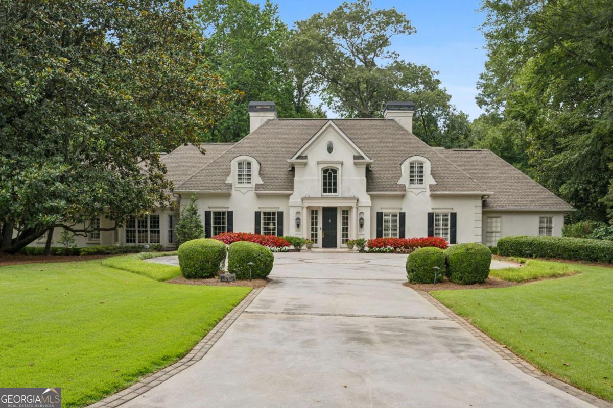 Nestled on 1.5 beautifully landscaped acres in coveted Kingswood, this exceptional residence blends timeless elegance with inviting warmth. Ideally located just moments from top private schools, major highways, and the Buckhead business district, the home offers a rare combination of convenience and seclusion. Tucked away in a serene, private setting, the property features lush, manicured grounds designed by Marcia Weber of Gardens to Love and a beautiful heated pool. Inside, the main level impresses with a light-filled vaulted great room and a bar that seamlessly connects to the grand two-story foyer, expansive living and dining rooms, and a generously sized kitchen-perfectly suited for both refined entertaining and relaxed family living. The luxurious primary suite is also on the main level, complete with a spa-like bath renovated in 2015 with heated floors, and a custom-designed closet. A versatile guest suite and a handsome library/office and another bar, complete the main floor. The sunlit terrace level offers flexibility with a second office, abundant storage, and a fully equipped in-law suite with a full kitchen. Additional amenities include a whole-house generator, upgraded pool equipment, an irrigation system, and a transferable Aquaguard warranty and a S.I.R. stucco bond-adding comfort, peace of mind, and enduring value to this exquisite home.