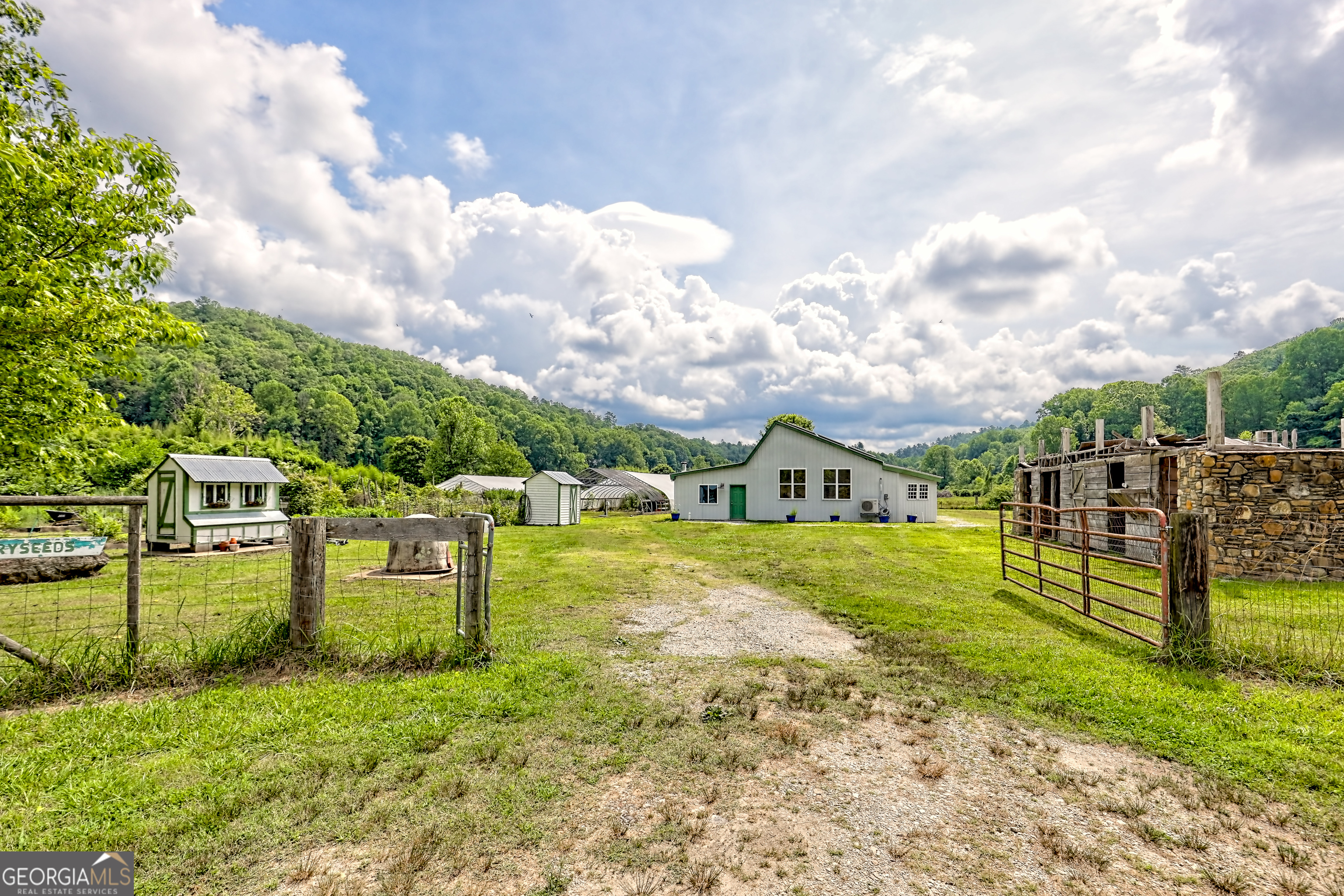 Discover endless possibilities with this 23.14 acre estate nestled in the scenic Stekoa Valley, just minutes from downtown Clayton, Georgia. A rare blend of usable flatland and elevated mountain acreage, this unique property offers both practicality and panoramic beauty. The lower 6.39-acre section rests mostly on the fertile valley floor with frontage on Stekoa Creek, ideal for sustainable agriculture. This prime farmland features rich, organic-practiced soil, perfect for growing a variety of crops, established berry bushes, herbs, and perennial plantings, all maintained using organic methods, multiple greenhouses, fencing, and strategically placed water hydrants for efficient cultivation, and a recently completed 4-bedroom, 3-bath barndominium conversion, suitable as a primary residence, farm manager's quarters, or rental opportunity. It features a solar panel array, outdoor entry full bath, and a wood burning stove. Across the road lies an additional 16.73 acres of wooded, mountainside terrain offering multiple building sites with breathtaking views-ideal for cabins, retreats, or expansion. Whether you're looking to start an organic farm, create a self-sufficient homestead, or simply enjoy peaceful rural living with agricultural potential, this property delivers.Live your dream of farming in the tranquil beauty of the Northeast Georgia mountains. Schedule your private tour today!