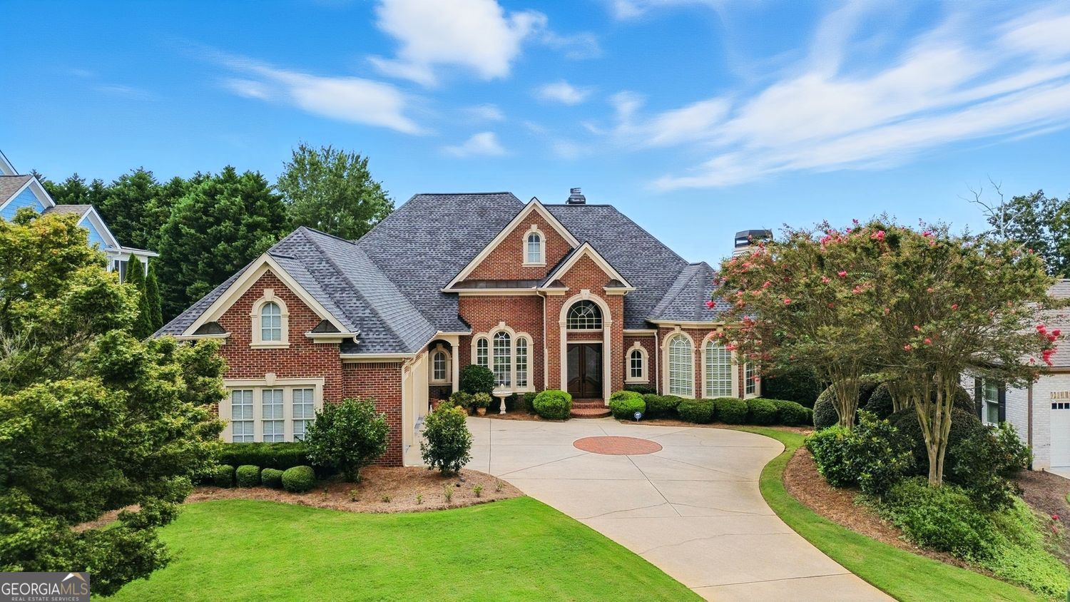 Be prepared to fall in love with this magnificent, custom designed, 4-sided-brick estate in the prestigious Harbour Point Yacht Club on the northern shores of Lake Lanier. Built by the famed Lee Wagner with exquisite detail and meticulous craftsmanship, this "Street of Dreams" home showcases timeless elegance and classic beauty, offering much to please and sure to impress the most discerning buyer. From the first glimpse, the manicured, up-lit grounds set the tone for the refined appointments within this stunning home. Upon entering you will be welcomed by many delights: polished hardwoods, sparkling chandeliers, coffered ceilings, crown moldings, masterful millwork, and 4 fireplaces! Just off the foyer French doors open to a handsome office with a cozy fireplace and unique 6-sided, faux-painted ceiling. The elegant dining room, complete with a butler's pantry, is open and lovely, and invites unforgettable entertaining. The expansive great room features a striking, wood-burning fireplace framed by custom cabinetry, a wall of sunlit windows, and access to the spacious deck affording sweeping, long-range lake views. The keeping room will become a favorite place to relax by the gas-logged fireplace, and opens to a delightful, screened porch. The breakfast room with its pretty, Restoration Hardware chandelier is a genial spot for casual dining. The showpiece kitchen is fabulous with everything your heart could desire: granite countertops, ample breakfast bar, walk-in pantry, Bosch dishwasher, Dacor double ovens, gas cooktop, a prep island, custom painted cabinetry, and a distinctive, scrolled hood vent. The conveniently located laundry room with a deep sink is adjacent to the spotless 3-car garage. The main level owner's suite is a true retreat, highlighted with an immense, spa-like bath offering separate, double vanities, a tiled, doorless shower, jacuzzi tub, and his and her closets. You will be charmed by the terrace level, and as football season begins, your friends and family will relish an invitation to your house to watch the big games. It's the perfect place to gather round the fantastic, full bar, cozy up to the fireplace, or spill out on to the walkout patio of the English garden backyard surrounded by gorgeous wrought iron fencing. If your guests are fortunate, perhaps they will receive an invitation to spend the night in one of 3 inviting bedrooms (one boasting its own huge sauna). A wine closet, generous cedar lined storage, workshop space with outside access, and additional storage complete this level. This impeccably maintained home with a 5-year-old architectural roof and new HVAC unit in 2024 ensures comfort and peace of mind. Living in Harbour Point affords an opportunity to enjoy a year-round, luxury lifestyle in one of the premier communities in Hall County. The unsurpassed amenities include an 8,000 square foot clubhouse, a marina, dining options, a cascading waterfall pool with lake views, basketball and pickleball courts, neighborhood events at the lakeside pavilion, and convenient golf cart access to walking trails along the 3 miles of unparalleled beauty of the Lake Lanier shoreline. The opportunity to reside in such a magical place is truly the stuff dreams are made of.