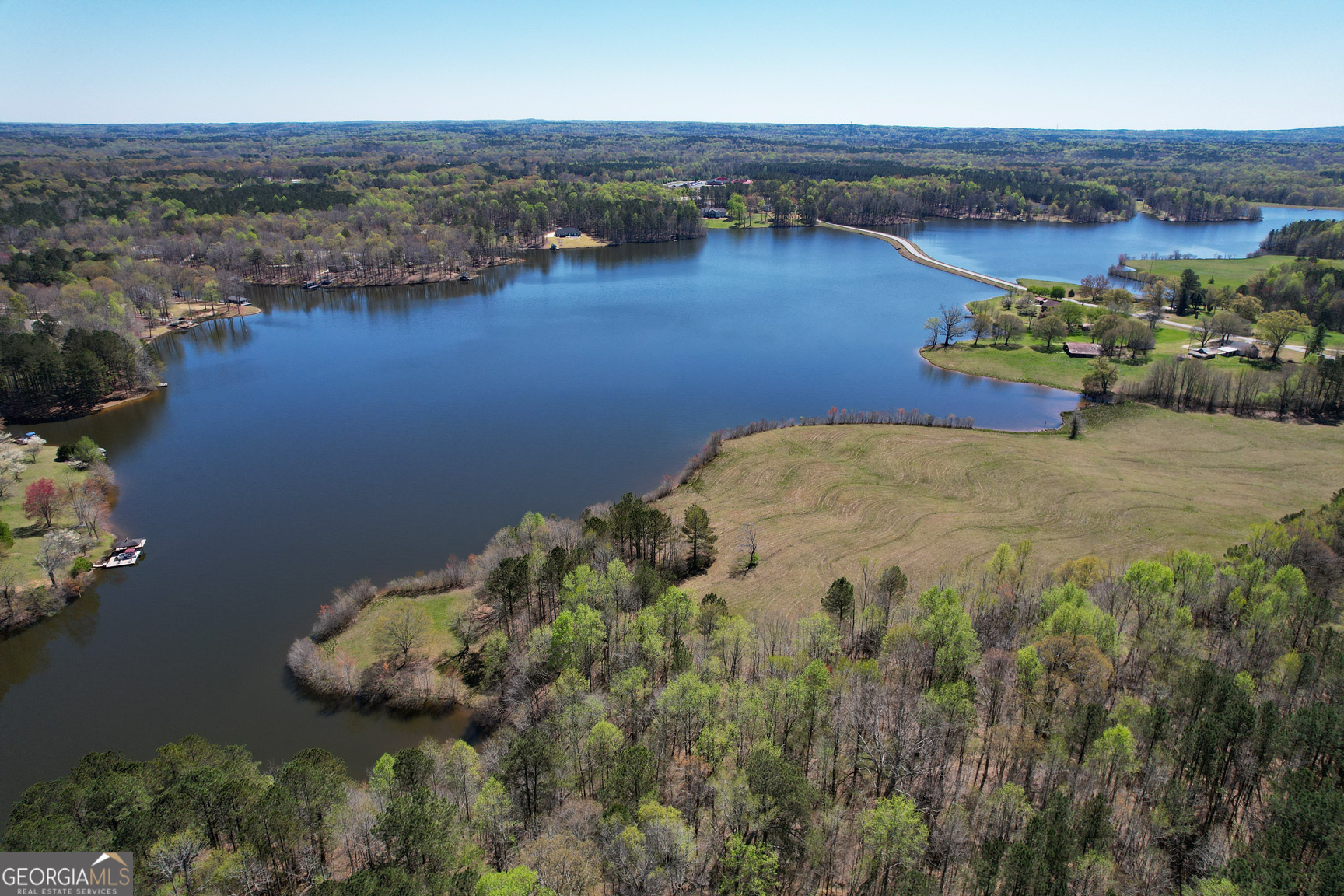Discover the epitome of serene living and boundless recreation with this enchanting 7.41-acre lot perched along the shores of Sharp's Creek Lake in the heart of Carrollton, Georgia. Offering a harmonious blend of convenience and natural beauty, this lot is an idyllic setting for your dream home or a developmental venture. Framed by lush hardwoods and featuring an impressive 800 feet (approximately) of waterfront, the possibilities for docking facilities, electric motor boating, and tranquil fishing are just the beginning. Beyond its recreational allure, the land is zoned for agricultural use, adding a layer of value for those interested in cultivation or sustainable living. Nestled in a haven for outdoor enthusiasts and sportsmen, the lot invites endless adventures, from hunting and fishing to trail riding amid the local wildlife. It is an ideal sanctuary for personal use as a private family compound or a lucrative investment opportunity for corporate retreats. Positioned mere minutes from downtown Carrollton, residents and visitors alike will enjoy the convenience of nearby shopping, dining, and cultural experiences. Moreover, with easy access to I-20, the vibrant life of Atlanta and its amenities is less than an hour's drive away, ensuring the perfect balance between secluded natural living and urban convenience. Step into a world where lifestyle meets nature, and every day offers an invitation to explore and cherish the outdoors. This is your opportunity to own a piece of paradise, where your waterfront dreams can become a reality in a setting that promises beauty, adventure, and convenience. Don't let this rare find slip away-your dream property on Sharp's Creek Lake awaits. Zoned: RES ACG