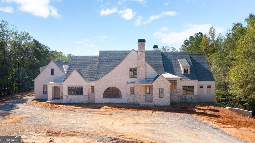 Old World Brick & Stone English Manor custom built by Smith & Kennedy perfectly situated on 5 acres in sought after Milton! Timeless open floor plan with 11ft ceilings on main featuring keeping room with fireplace, huge family room with iron metal doors, office on main level along with task room/laundry room and elevator servicing all three floors. Designer kitchen with dual Sub-Zero refrigerators, Wolf range, custom inset cabinetry, quartz/marble countertops and oversized island. Back prep kitchen with additional oven, dishwasher, ice machine, warming drawer and microwave. Owners suite on main with spa like bathroom, frameless glass walk in shower with soaking tub, dual vanities and his & hers closets. Massive covered porch with fireplace, outdoor kitchen with pizza oven, big green egg, skillet, sink, ice machine and under counter refrigerator. Private backyard with 20x40 heated saltwater pebble tec pool with raised spa, pickle ball court and pool bathroom. Secondary level offers three ensuite bedrooms and flex space over the five car garage with an additional bedroom/bath, loft or playroom. Future terrace level features ensuite bedroom, wine cellar, fitness center with full bathroom, rec room, billiards room with bar, home theatre and ample unfinished storage space.