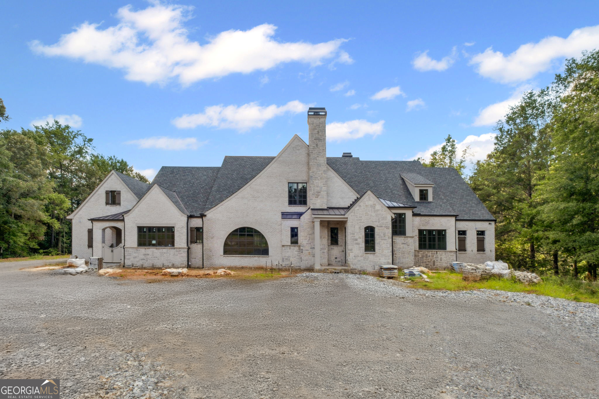 Old World Brick & Stone English Manor custom built by Smith & Kennedy perfectly situated on 5 acres in sought after Milton! Timeless open floor plan with 11ft ceilings on main featuring keeping room with fireplace, huge family room with iron metal doors, office on main level along with task room/laundry room and elevator servicing all three floors. Designer kitchen with dual Sub-Zero refrigerators, Wolf range, custom inset cabinetry, quartz/marble countertops and oversized island. Back prep kitchen with additional oven, dishwasher, ice machine, warming drawer and microwave. Owners suite on main with spa like bathroom, frameless glass walk in shower with soaking tub, dual vanities and his & hers closets. Massive covered porch with fireplace, outdoor kitchen with pizza oven, big green egg, skillet, sink, ice machine and under counter refrigerator. Private backyard with 20x40 heated saltwater pebble tec pool with raised spa, pickle ball court and pool bathroom. Secondary level offers three ensuite bedrooms and flex space over the five car garage with an additional bedroom/bath, loft or playroom. Future terrace level features ensuite bedroom, wine cellar, fitness center with full bathroom, rec room, billiards room with bar, home theatre and ample unfinished storage space.