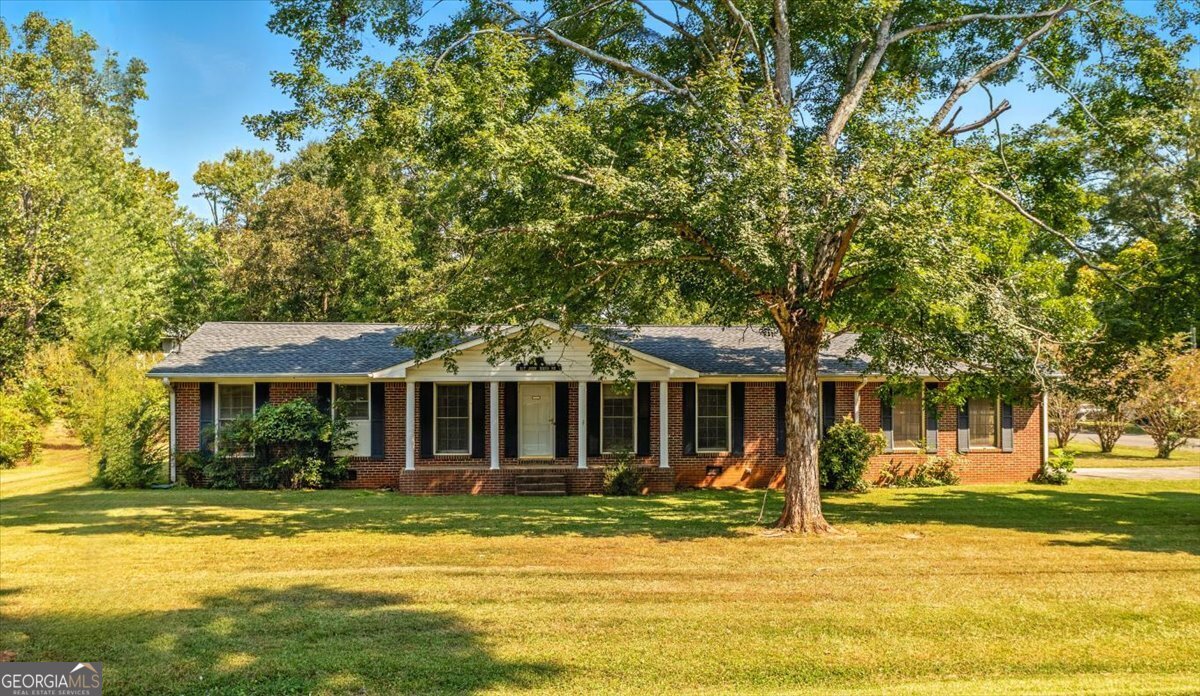 A classic 1968 Four-Sided Brick Home with so much potential can be found at 217 E John Hand Rd. This 4 bedroom, 2 bathroom brick ranch sits on a spacious corner lot and offers a great mix of timeless character and opportunity for personalization. It was built in 1968 and has a traditional layout with defined rooms and multiple living spaces to fit your lifestyle. Step inside and you'll find a warm family room centered around a statement fireplace, a cozy den, and a kitchen with bay window views of the backyard. Two potential dining areas provide flexibility for casual meals or more formal gatherings. The sunroom located off the family room is ideal for year round enjoyment and overlooks the mostly level back yard. The home's bathrooms have vintage charm, and ready for updates to suit your style. There is a convenient mudroom with laundry tucked away as you enter in through the carport area. The .59+/- acre lot includes a storage building and plenty of usable space for play, gardening, or outdoor entertaining. Recent updates bring peace of mind: a new HVAC (2023) and roof (2024). With a little sweat equity, this home is primed to shine. Centrally located just 1 mile from Kroger, 2 miles from Walmart, and close to local restaurants, schools, and parks. Easy access to Hwy 27 for commuting to Rome, Buchanan, or Hwy 278 to Rockmart. Don't miss this chance to create your dream home with modern touches while preserving its classic character. Schedule your showing today! *All information deemed reliable but buyer's responsibility to verify.