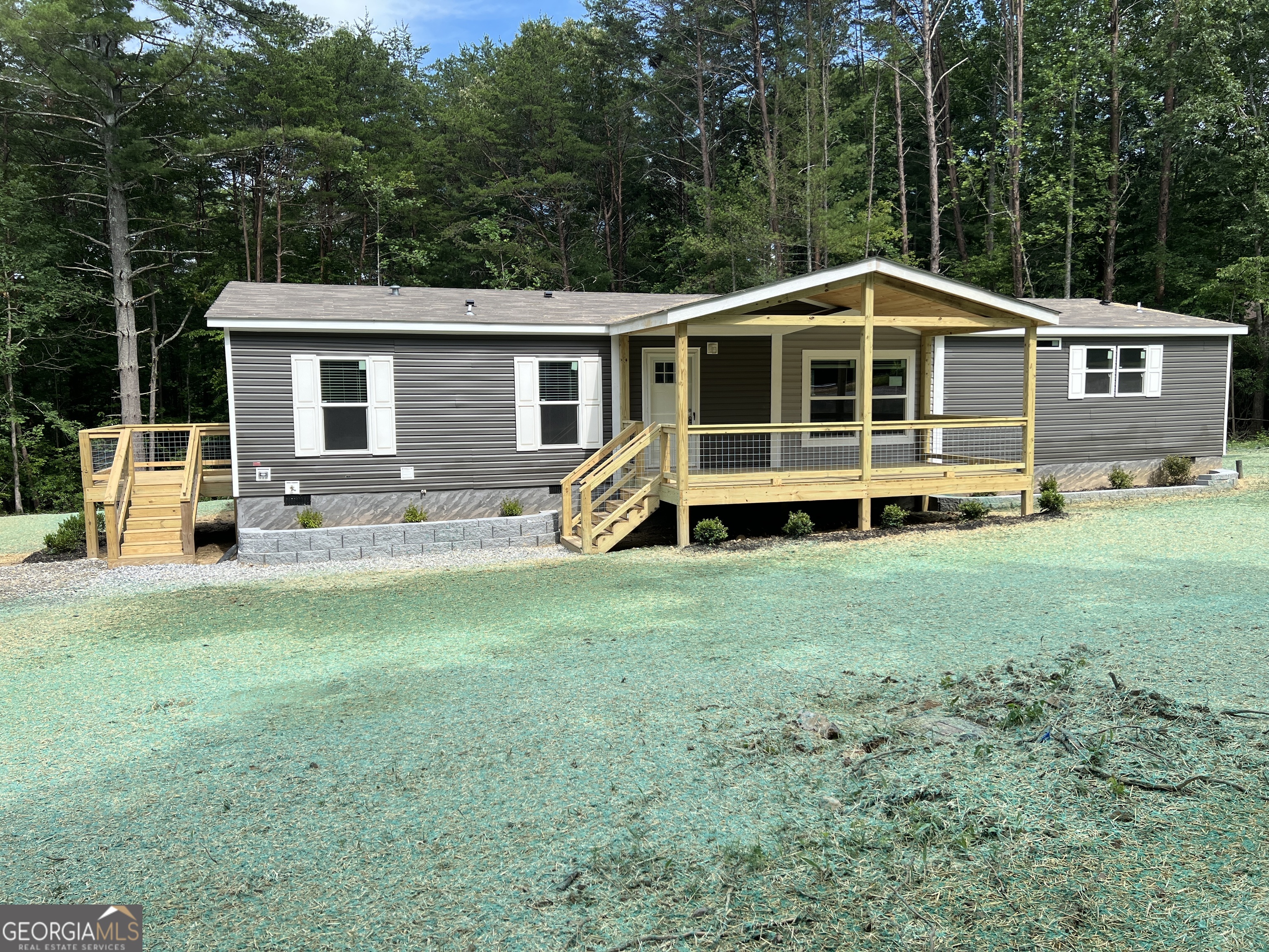 Here is a great opportunity to own a brand new home on 1.5 acres of property! Easily accessible from US-515, making your commute easy to anywhere. Come see this nicely located and perfectly outfitted NEW manufactured home. This home is loaded with extras, and designed for low maintenance living. It is prewired for solar power and dehumidifier, if you decide to add them later. The water heater and HVAC can both be controlled using an app, if you choose. Step onto your covered front porch and walk into this beautifully finished 1804 sq ft , 3 bed and 2 bath home. The living room will welcome you with beamed ceilings, and an open concept design that's loaded with comfort and convenience. The kitchen has a fully functional island with storage everywhere, and plenty of barstool seating space. Loads of cabinet space and a hidden, spacious walk in pantry. All appliances are stainless and easily maintained in this fully electric home. Relaxation will be easy when you step into the master bedroom and bath - complete with tile shower and soaking tub. With double vanities and built ins; the master bath has loads of room to move around, and includes a large walk in closet. This home also is designed to add a garage on the end, if you so choose. This home has it all! It even includes a spacious laundry room with a dog wash station! Call today to check out this wonderful home! Please watch the showing video as more can be seen. Call Roy Rose for a showing today 706-968-1652