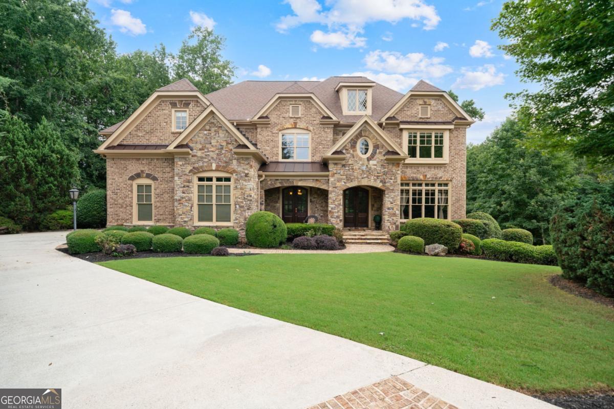 Welcome to this breathtaking FOUR-SIDED BRICK, covered natural stone entryway residence where timeless luxury and elegant design greet you from the moment you arrive. Located on a cul-de-sac in the prestigious gated TURNBERRY community, with the most HIGHLY RATED SCHOOLS and LOW TAX Forsyth Co. Walking into a wide foyer to be greeted with the full natural light that this home has to offer. The main floor showcases rich hardwood flooring, private home office with wood paneling and coffered ceiling , the family room impresses with its dramatic coffered ceiling, built-in custom cabinetry and the primary fireplace offering a warm and inviting space for relaxation, open to the great room with its own fireplace and the views of the massive backyard. Soaring 11- to 12-foot ceilings, and exquisite CROWN MOLDING throughout. The GOURMET KITCHEN is a showpiece, featuring ceiling-height cabinetry that blends style and function, while adjacent to formal dining room comfortably seats 12+ guests-perfect for hosting unforgettable gatherings. The main level is complete with a beautifully appointed in-law suite with its own private ensuite bathroom. Step outside to an extra-large Trex deck overlooking a fully leveled, professionally landscaped 100% PRIVATE almost 1 acre backyard-an ideal setting for outdoor entertaining or peaceful retreat. Beneath it all lies a massive unfinished basement with high ceilings and open space, ready to be transformed into your dream gym, theater, game room, or additional living suite. Upstairs, the home continues its theme of grandeur with 10- to 11-foot ceilings, detailed crown molding, and a BONUS ROOM , MASSIVE MASTER SUITE , and three more bedrooms, each with its OWN FULL ENSUITE BATHROOM, ensuring comfort and privacy for all. The master suite is a true sanctuary, generously sized with a cozy seating area anchored by a FIREPLACE, a PRIVATE BALCONY for morning coffee or evening stargazing, and a spa-inspired bathroom adorned with NATURAL STONE finishes that evoke tranquility and indulgence. HIS AND HERS closets offer boutique-style storage, completing a retreat that redefines luxury living. Completing this exceptional home are 3 covered garage spaces Every inch of this residence has been thoughtfully crafted to deliver refined elegance, and timeless comfort.