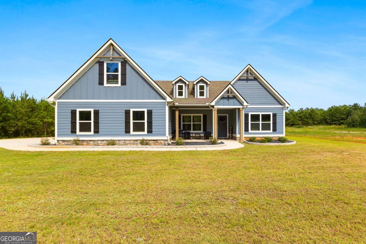 This beautiful ranch style home sits on 7.7+/- acres and boasts an open-flow design, featuring a seamless transition from the family room to the kitchen and dining area. The dining area is highlighted with accent trim details, adding a touch of elegance. The kitchen is equipped with beautiful shaker-style cabinetry, built-in stainless steel appliances, and a stylish tile backsplash. A standout feature of the home is the Keeping Room, which includes a fireplace with designer selections and an abundance of natural light. The split bedroom layout offers privacy, with a spacious master suite that includes a large closet and a luxurious master bath featuring a designer-tiled shower, garden tub, and double vanity. Two guest rooms on the main level share a secondary bathroom, while upstairs you'll find an additional bedroom and bathroom, perfect for guests. The home also includes a covered back patio and a separate covered sitting area, ideal for outdoor relaxation.