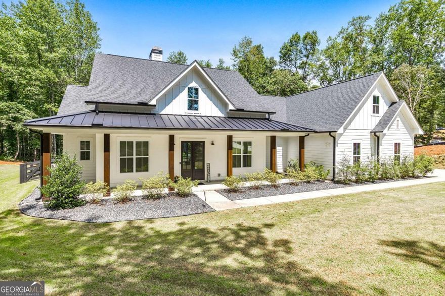 Looking for a home that checks all of your boxes? Look no further! Welcome to this stunning 2023-built modern farmhouse, offering 4 bedrooms and 3 baths on a picturesque 1.5 acre lot in a prime Woodstock location. From the moment you step onto the charming rocking chair front porch, you'll feel right at home. Inside, the open-concept design is filled with natural light, showcasing a bright and airy living space that's perfect for both everyday living and entertaining. The chef's kitchen is a true showpiece with an expansive island, quartz countertops, stainless steel appliances, a farmhouse sink, and a large walk-in pantry. An office sits just off the main living area, providing a quiet space to work from home. The main-level primary suite is a luxurious retreat with a spa-like bath boasting a double shower and dual vanities. The oversized walk-in closet is a dream and connects directly to the laundry room for added convenience. Two additional main-level bedrooms share a beautifully designed hall bath with a double vanity, while a versatile flex room with a dog door to the backyard adds extra function. Upstairs, a private bedroom and full bath create the ideal suite for teens, guests, or extended family. Thoughtful details include 8-foot solid core doors on the main level, soft-close cabinets/drawers throughout, a tankless gas water heater, and a washer and gas dryer included. Outside, the expansive covered back porch and extended patio overlook the level, fenced backyard, providing the perfect backdrop for weekend barbecues, playtime, or simply relaxing while kids and pets enjoy the space. Blending modern luxury with timeless farmhouse charm, this home is designed for comfort, style, and lasting memories. With its incredible features and inviting spaces, it's a place you'll be proud to call home for years to come!