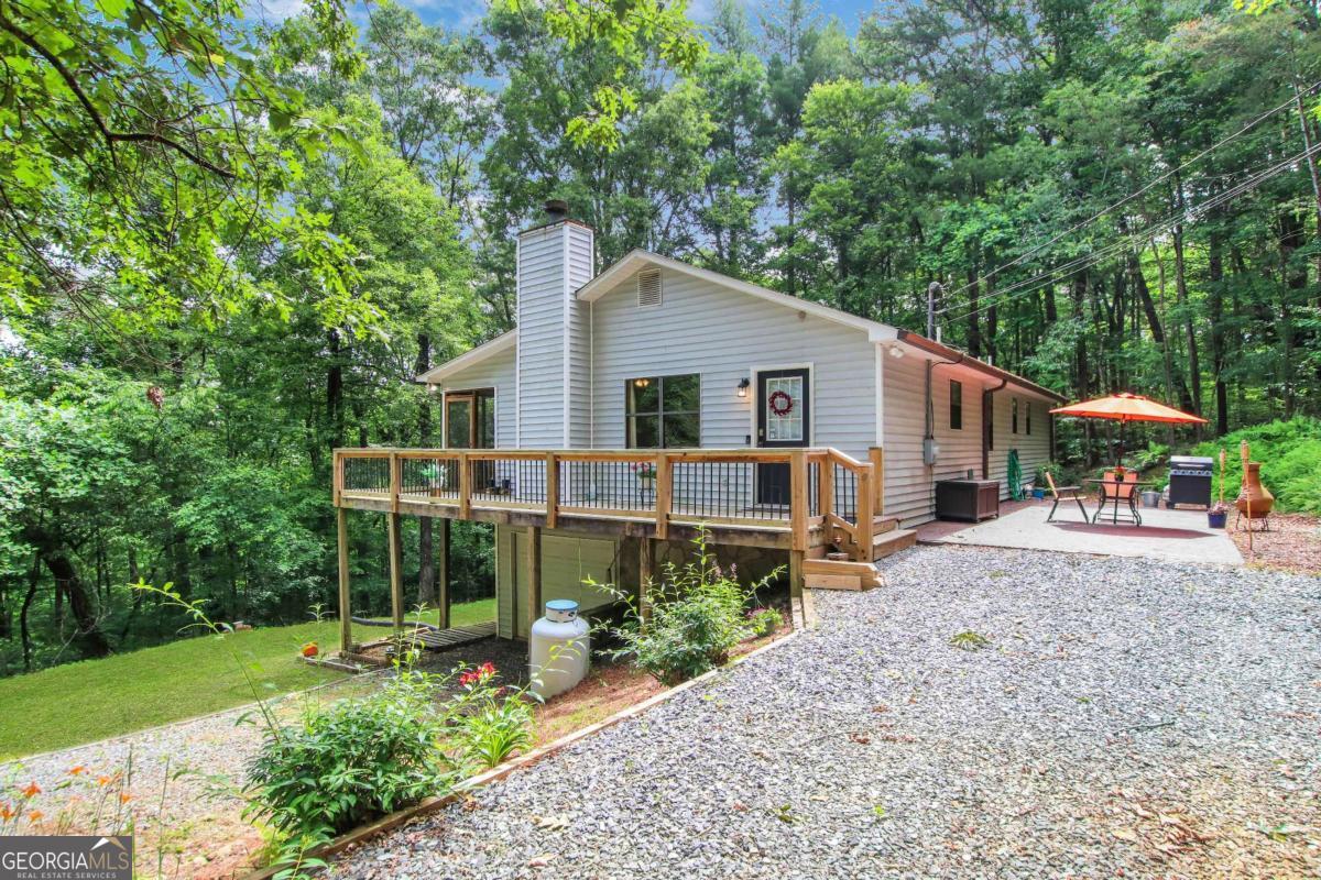 The mountains are calling, and this is the one you've been waiting for. Nestled on 2.4 private acres with seasonal views of the Blue Ridge Mountains, this charming custom home invites you to slow down and stay awhile. Located just off the winding country roads of North Georgia, it offers a perfect mix of peace, play, and practicality. The main level welcomes you with hardwood floors, an open-concept layout, and a thoughtfully designed kitchen featuring extra-deep cabinetry and a custom expandable island with seating. Three bedrooms and two full baths, including a spacious primary suite with private deck and patio access, offer easy one-level living. The terrace level expands your options with a fourth bedroom, full bath, and two large flex spaces; ideal for a media room, game room, or guest retreat. Outdoor living shines here, from the full-length screened porch for sipping coffee with a mountain view, to the fire pit area and side yard perfect for ladder ball, volleyball, or relaxing under the stars. Whether you're dreaming of a full-time escape or the perfect weekend getaway, this home checks all the boxes. Welcome to the mountain life.