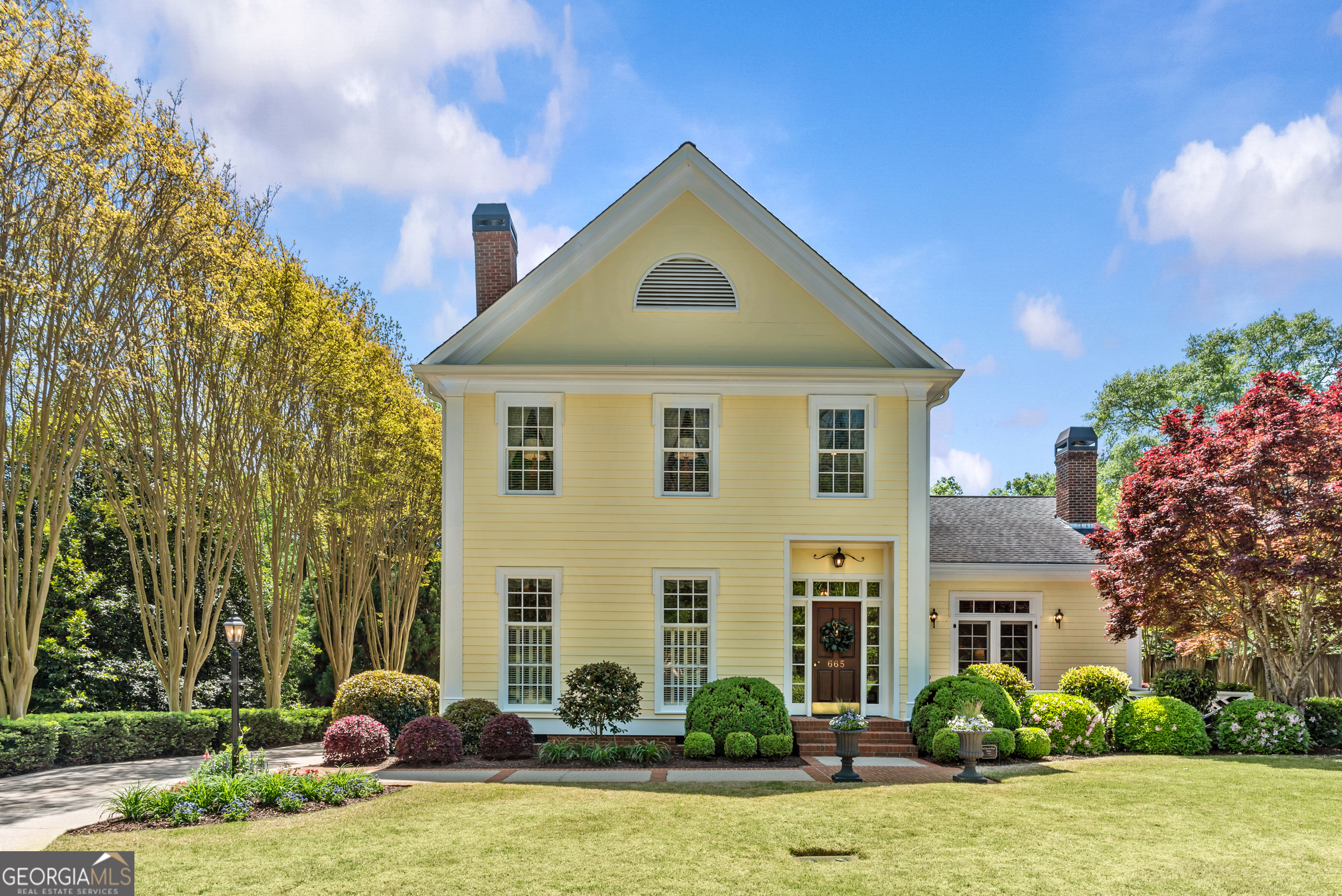Experience the timeless appeal of this 3-bedroom, 3.5-bath residence in the heart of Madison's Historic District. Designed in the federal farmhouse style by a historic preservationist and brought to life by a respected local builder, this custom home blends classic architecture with modern comfort. Meticulously cared for, it features antique heart pine floors, elegant crown molding, soaring 10-foot ceilings, and a spacious main-level master suite. A wide, welcoming entry hall offers a clear sightline through the home, drawing you in. The living room showcases rich architectural detail, with paneled walls, scalloped fireplace niches, and a seamless connection to the dining room through a graceful cased opening. The family room's beamed ceiling and paneled walls with glass display shelving create a warm, inviting atmosphere, and double doors open to a Chippendale-fenced brick patio and terrace. Surrounded by blooming gardens and lush greenery, this outdoor haven is perfect for alfresco meals, relaxing afternoons, or evening gatherings. The cheerful eat-in kitchen features stainless steel appliances, abundant cabinetry, and recessed lighting. Nearby are a convenient laundry room and a generous two-car garage with built-in storage. Upstairs, two large bedrooms each offer ensuite baths and walk-in closets for comfort and privacy, along with a versatile bonus room ideal for an office or craft space. A walk-in attic provides even more storage. Set in a friendly, walkable neighborhood, this home is just one block from Hill Park's tennis and pickleball courts, two blocks from the Madison Morgan Cultural Center, and a short stroll to the vibrant town center. It also offers easy access to Athens, Lake Oconee, and Atlanta. This is a rare chance to own a piece of Madison's history-beautifully updated for modern living.