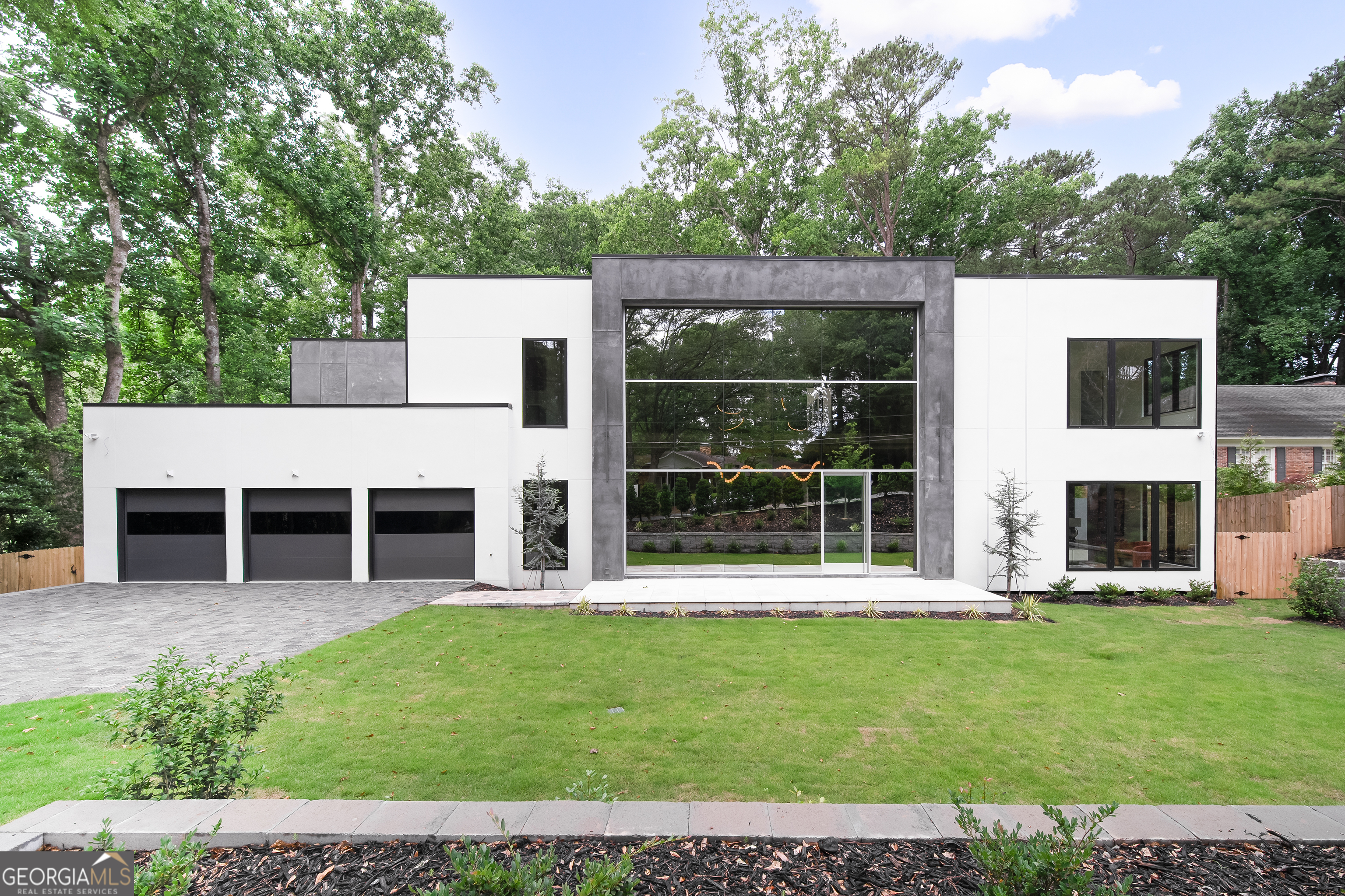 This stunning ultra-modern new construction masterpiece now complete and move-in ready in Chastain Park. Step into a breathtaking two-story entrance featuring handcrafted floating staircases, and warm, sultry textures of Venetian plaster and designer wallpapers. An awe-inspiring custom commercial window wall allows sunlight to pour into the incredible entry way with an immediate view to the pool beyond. The chef's kitchen is a culinary haven, equipped with Wolf and Subzero appliances, including a Wolf gas cooktop and double ovens in the main kitchen. Behind the main kitchen, a full prep kitchen awaits, complete with a second Wolf Range, Subzero Fridge, Dishwasher, sink, and wine fridge, providing the perfect space for a private chef or catering. Sonos invisible speakers are already installed in the living room and controlled via smartphone to set the mood for your day. The ultra-luxurious dining area offers a double- sided glass wine feature wall, perfect for entertaining. Slide open the many multi-slide doors that bring the outdoors in - step out to a stunning patio and heated salt-water pool and spa. The main level boasts a junior primary suite with spacious walk-in closets featuring custom-built cabinets and shelving, ensuring storage needs are met with elegance and practicality. Upstairs, the large primary oasis awaits, featuring oversized his and hers closets with built-in cabinets and shelving. The spa-like primary bath is a sanctuary of relaxation, adorned with curved glass doors and covered in stunning porcelain slabs. This home is designed for modern living, with every convenience at your fingertips. It is fully integrated into a SmartHome system, offering Lutron automation throughout. The 3-car garage is wired for EV charging stations in all three bays, catering to electric vehicle enthusiasts. In the basement, a spacious rec room awaits, fully wired for a 7.1 home theater system, providing endless entertainment possibilities. Don't miss the opportunity to make this exceptional residence your own, where modern luxury and thoughtful design converge to create an unparalleled living experience. Just steps from Chastain Park itself, this home offers a private and secluded feel, while offering the luxurious conveniences of Buckhead just minutes away.