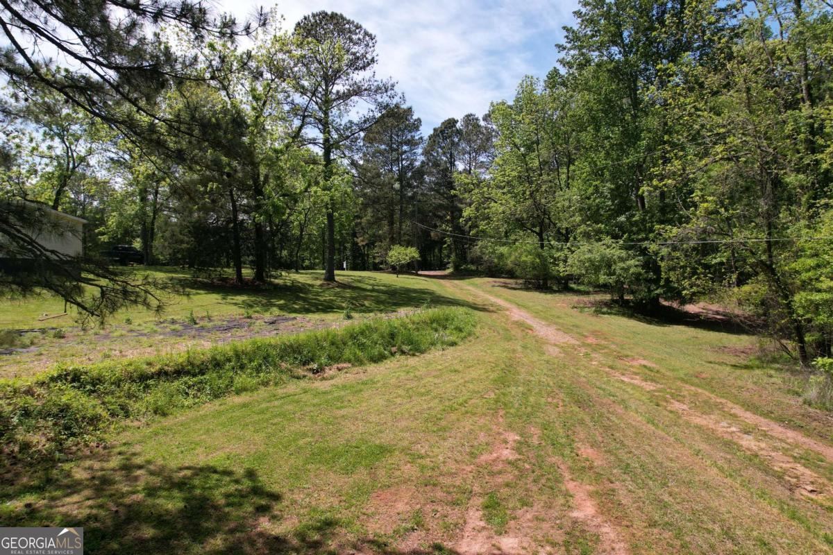 Exceptional opportunity for building your dream home(s) on a gorgeous piece of SERENITY in East Forsyth, minutes from Lake Lanier! Highly desirable area. With Fourmile Creek winding through the back section of this property and A1 zoning in place, this parcel offers the flexibility to develop a private estate, mini compound, or multiple homesites. Property is already equipped with THREE build sites, complete with existing electric, power, water and septic connections. The groundwork is set for immediate expansion. The existing mobile home provides a place to live or rent while you build. EASY instant rental income! Nestled on a quiet, secluded road-yet you're just minutes from Lake Lanier's beaches, top-rated schools, parks, and all the amenities of Cumming plus easy commute to Gainesville and Dawsonville. Whether you're envisioning custom homes, your dream estate, or a small farmstead, this property checks all the boxes: location, infrastructure, and development potential. Opportunity to purchase addl 6 acres in the very back for a total of 10.68 acres. Appointment is required.