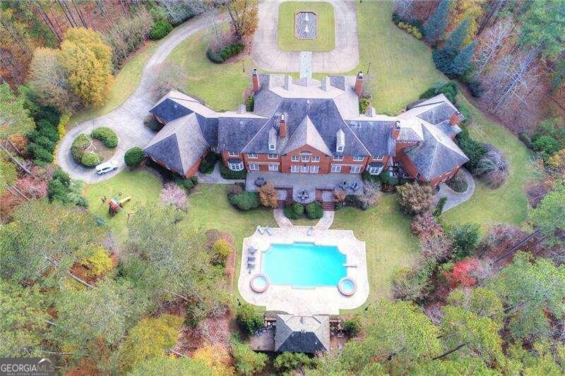 Within the esteemed enclave of North Valley and heart of Milton, lies a masterpiece of luxury estate living, sprawling across an impressive expanse of +/- 10 acres. This Georgian all-brick mansion, epitomized by the Great Gatsby, is a monument to architectural finesse and unmatched refinement. Spanning more than 12,000 square feet, the estate presents an assemblage of magnificent living and entertaining spaces, crowned with 12-foot high ceilings, the highest quality of millwork and design, an illustrious slate roof, genuine copper gutters, and an elevator to gracefully ascend through its storied levels. Designed for the consummate host, the estate boasts a 54-foot swimming pool, complemented by two spas and a pool house with a kitchenette, setting the stage for gatherings of unmatched elegance and joy. At the heart of this splendid domain is a gourmet kitchen, a chef's dream, outfitted with triple islands, four dishwashers, four ovens, and a walk-in pantry, 2 fully equipped bar areas, poised to accommodate the most lavish of feasts and intimate gatherings alike. Inside guests are greeted by a dual staircase, a dome lighted ceiling, marble-tiled entryway, six fireplaces and an exquisite office space/cigar lounge, adorned with illuminated bookcases. Majestic living quarters, featuring a master suite on main, four grand bedrooms up, each with ensuite baths and walk-in closets, alongside a basement area exquisitely finished with a sauna, spa, and guest quarters. Outside youCOll find magnificently manicured grounds that promise solitude and a picturesque setting for outdoor entertaining. Within a locale that marries the tranquility of rural grandeur with the convenience of proximity to Milton and AlpharettaCOs plethora of amenities, this estate also features a four-car garage and ample additional parking, emphasizing the utmost in construction quality with a lens focused firmly on luxury and seclusion. This estate stands as an invitation to those of discerning taste, seeking a residence that not only promises, but delivers an unparalleled lifestyle of elegance and exclusivity.