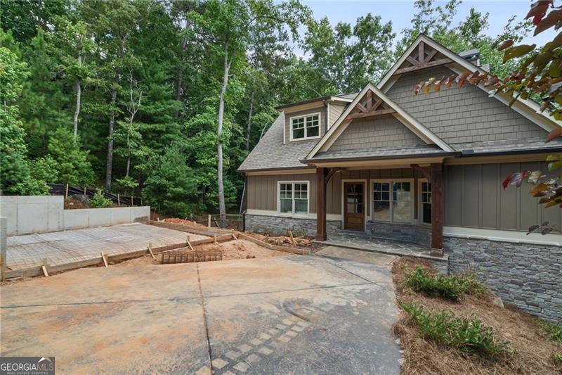 This 5 BR - 3 1/2 Bath design home is new construction and shows like a model with a brand new attached 2 car garage addition is in process, located in the very desirable cobblestone paved neighborhood 'Choctaw Village' near the Clubhouse in Big Canoe. Stunning Cedar beams in the family room. Hardwood flooring, upgraded lighting and custom features throughout. Enjoy the gorgeous two-story stone fireplace with ever changing, seasonal wooded views from the wall of windows. Custom Wellborn cabinetry in the kitchen with quartz counter tops, island with additional seating, stainless steel hood, 5 burner gas range/oven with air fryer feature. Open concept floor plan with access to the screened in porch with outdoor stone fireplace. Powder room features one-of-a-kind live edge vanity with vessel sink. Master on main features French door access to your outdoor living areas. His and hers walk in closets, modern soaking tub, custom Wellborn vanity and custom tile shower, quartz countertops. Two additional bedrooms and Jack and Jill bathroom on second level. Fully finished terrace level featuring custom wet bar with stack stone wall, butcher block countertop and custom floating shelving. Stacked stone wine cellar ready for your unique customization. Two additional bedrooms with full bath. Terrace level features high end LVP flooring, 8 ft interior doors, wall of windows and access to outdoor covered decks and patio. Garage/2 addition is attached via breezeway and well underway with a completion date of October 30th, 90 days or less. This is the only home currently for sale in all of Choctaw Village and close to all of the amenities, including walking trails out of your backdoor and within walking distance to the newly renovated and expanded Clubhouse and recently modified Golf Course, Choctaw and Creek both. This new home will come with a 1 Year Builder Warranty and is situated on a private cul-de-sac and located just minutes from the main gate entrance for ease of access in and out the community for good measure. Come see for yourself!