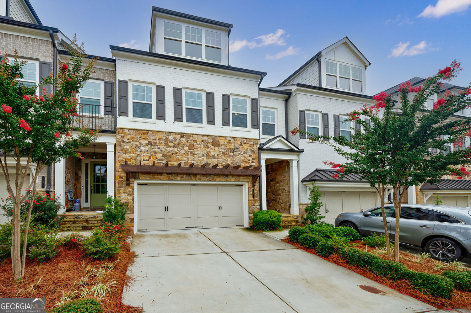 From the moment you step into this custom-built townhome, you'll appreciate the thoughtful design and high-end finishes throughout. Wide plank, hand-scraped hardwoods set the tone, while the chef's kitchen steals the show with quartz countertops, double wall ovens, a sleek microwave drawer, and tall 42" upper cabinets topped with elegant glass-front display cabinets for added storage and style. Very desirable in the community, this home is one of the very few in the neighborhood with a basement. Featuring 10 foot ceilings on main, the Concord floor plan offers an open, sun-drenched main level with a seamless flow to the private backyard and elevated deck-perfect for morning coffee or evening entertaining. The separate dining room and adjoining family room create the perfect setting for hosting family and friends, while the oversized island serves as the heart of the home-ideal for meal prep, casual dining, or just gathering around with good company. Storage is no afterthought here-every level offers generous closets, with custom shelving behind nearly every door. And yes, it's elevator-ready. Upstairs, you'll find an expansive landing (think reading nook or homework station), along with a spacious primary suite that includes a cozy sitting room with an electric fireplace-ideal for Netflix marathons or your dream home office setup. The spa-inspired ensuite bath features dual vanities, a frameless glass shower with bench, and a soaking tub to unwind in style. The custom closet flows effortlessly into the connected laundry room-smart and convenient. Two additional upstairs bedrooms and a full bath offer flexible space for guests, kids, or whatever life throws your way. The lower level features a fourth bedroom, full bath, large family room, and bonus flex space-perfect for a gym, hobby room, or game night central. Situated directly across from the expansive community green space, you will enjoy resort-style amenities including two pools, tennis and pickleball courts, dog parks, walking trails, a community garden, and a clubhouse that hosts everything from food trucks and wine tastings to fitness classes and live music on the green. Located in the sought-after gated community of Harlow, you're just minutes from Avalon, downtown Alpharetta, historic Roswell, and the Ameris Bank Amphitheatre. Luxury, comfort, and connection-it's all waiting for you at Harlow.